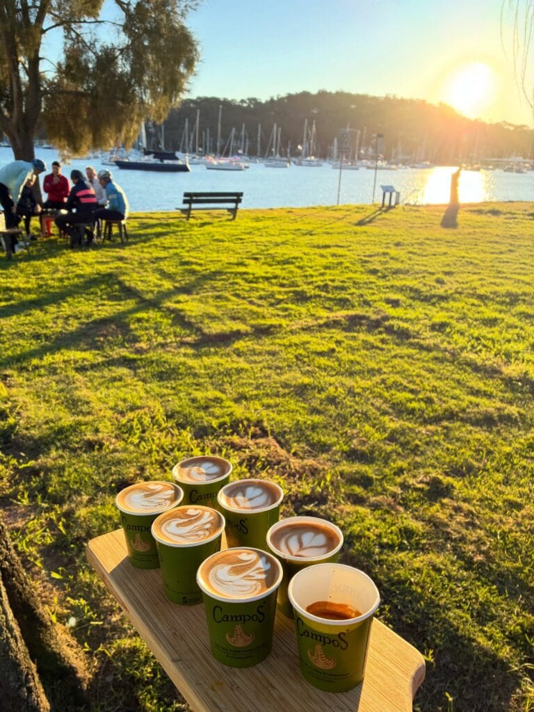 Campos coffees with latte art on a waterfront bench beside Gibson Marina at 8 Knots cafe, Bayview Sydney