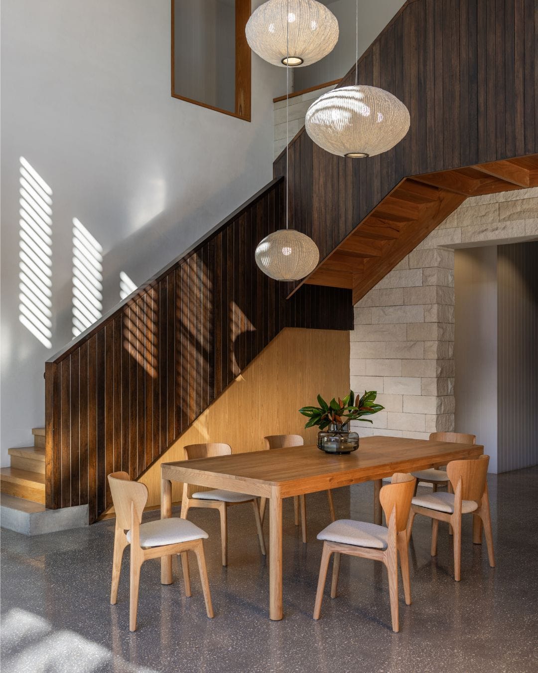 A modern dining room featuring pendant lights and timber chairs from The Modern.