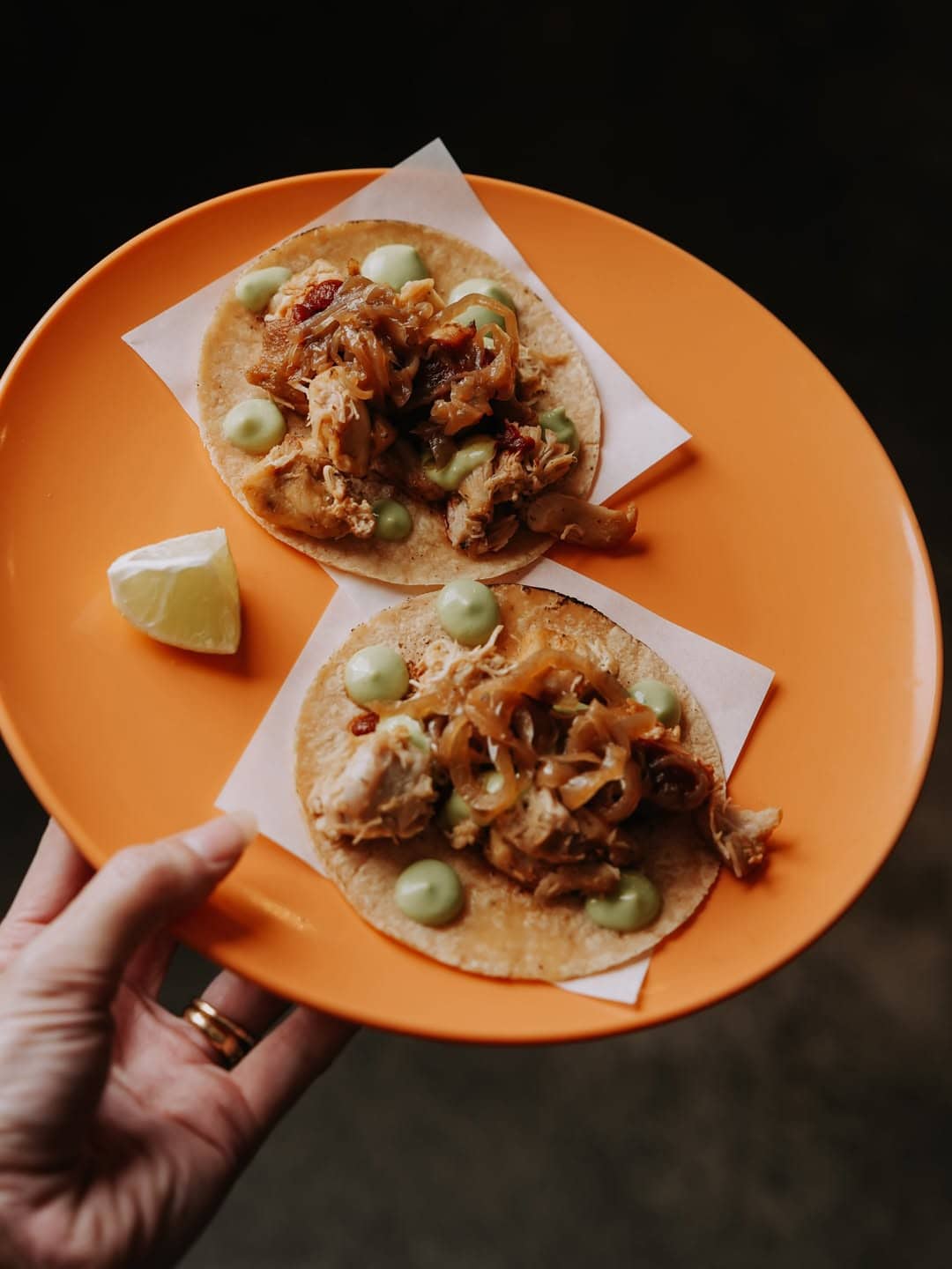 Two chicken tacos and a slice of lime on an orange plate at Baja in Brisbane.