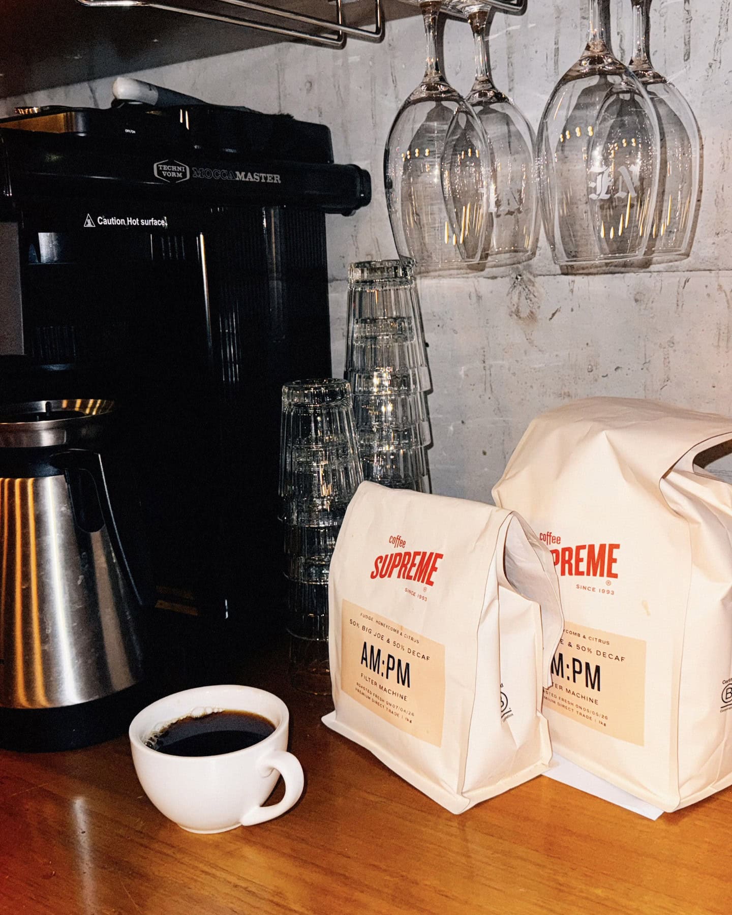 Bags of Supreme coffee beans next to a cup of filter coffee at Never Enough in Fortitude Valley.