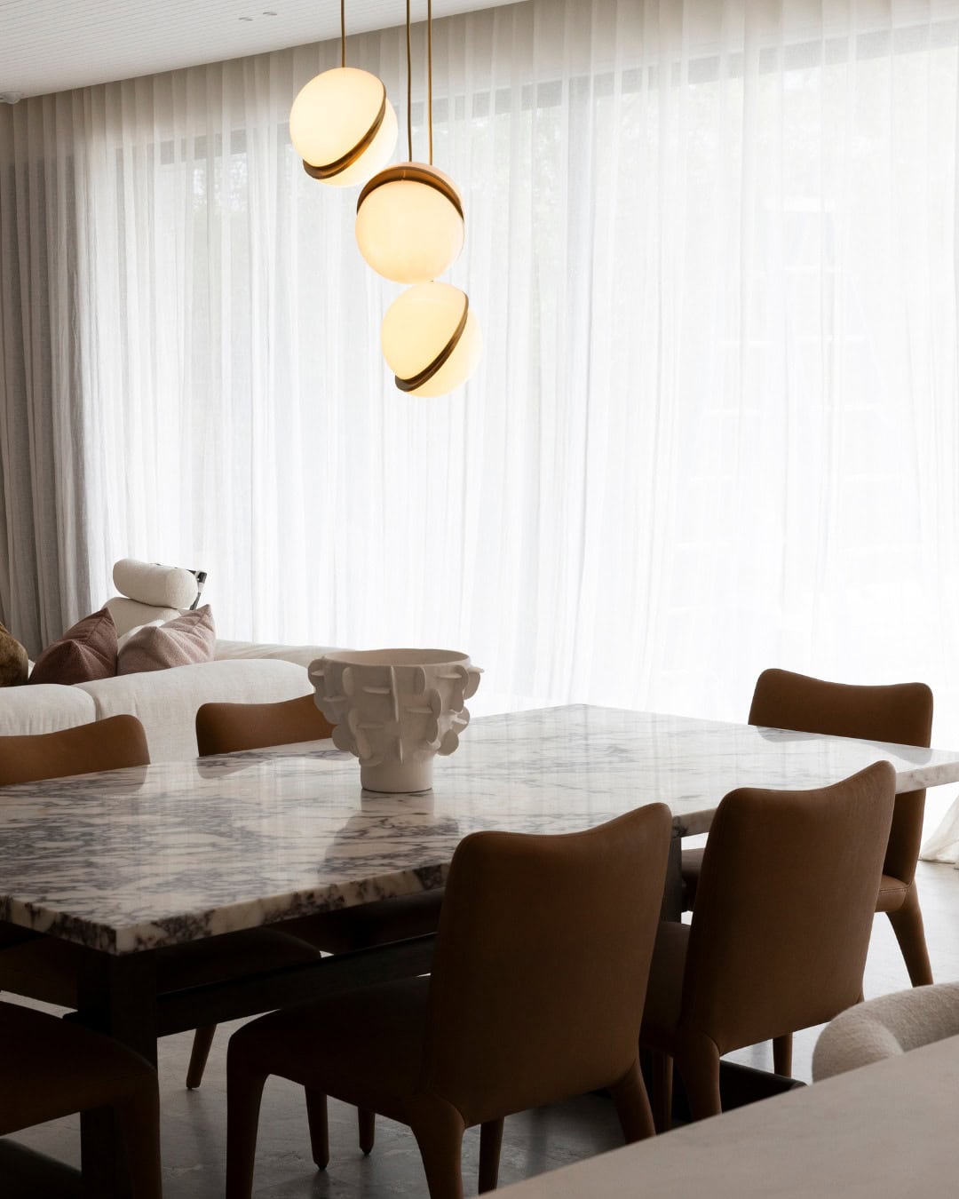 A marble dining table with pendant lighting above from Coco Republic.