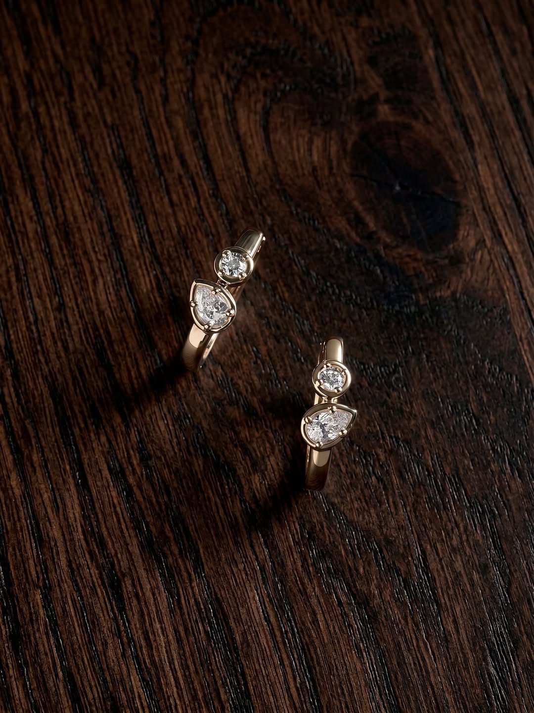 Two diamond hoop earrings from Claude & Me against a black backdrop.