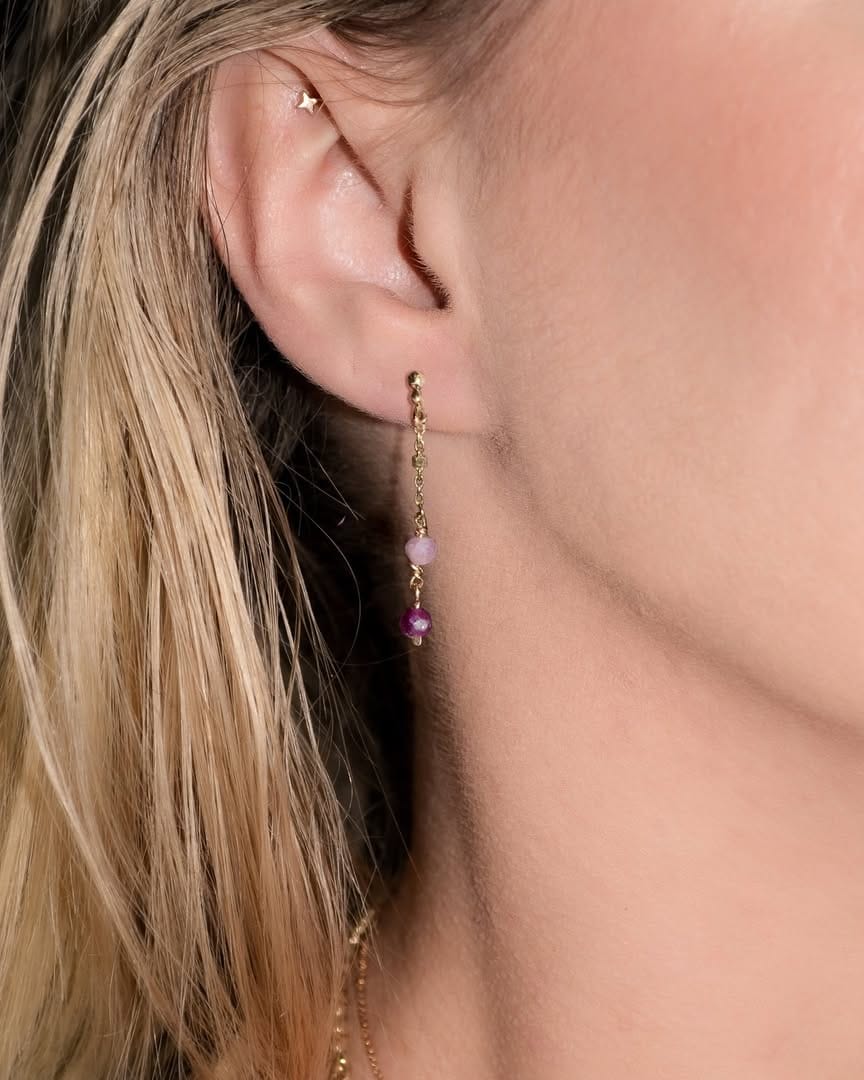 A delicate dangling earring on an ear from Rebellious Grace .