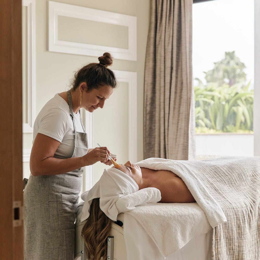 A woman receiving a facial in her hotel room at Eleme Spa at Crystalbrook Byron.