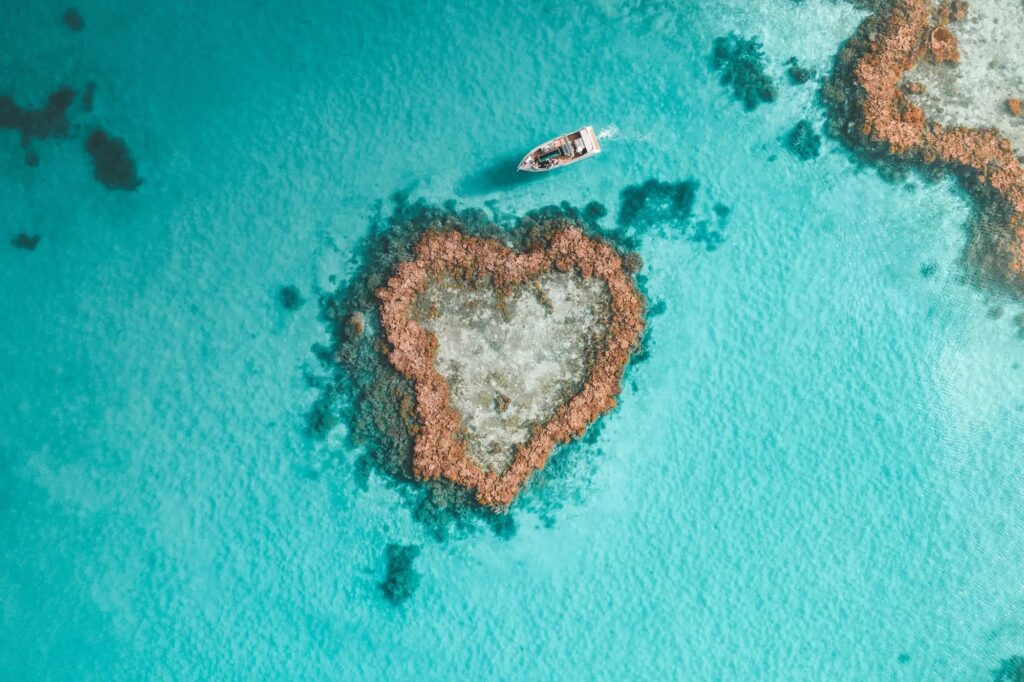 Aerial view of heart-shaped Heart Reef with boat in the Whitsundays