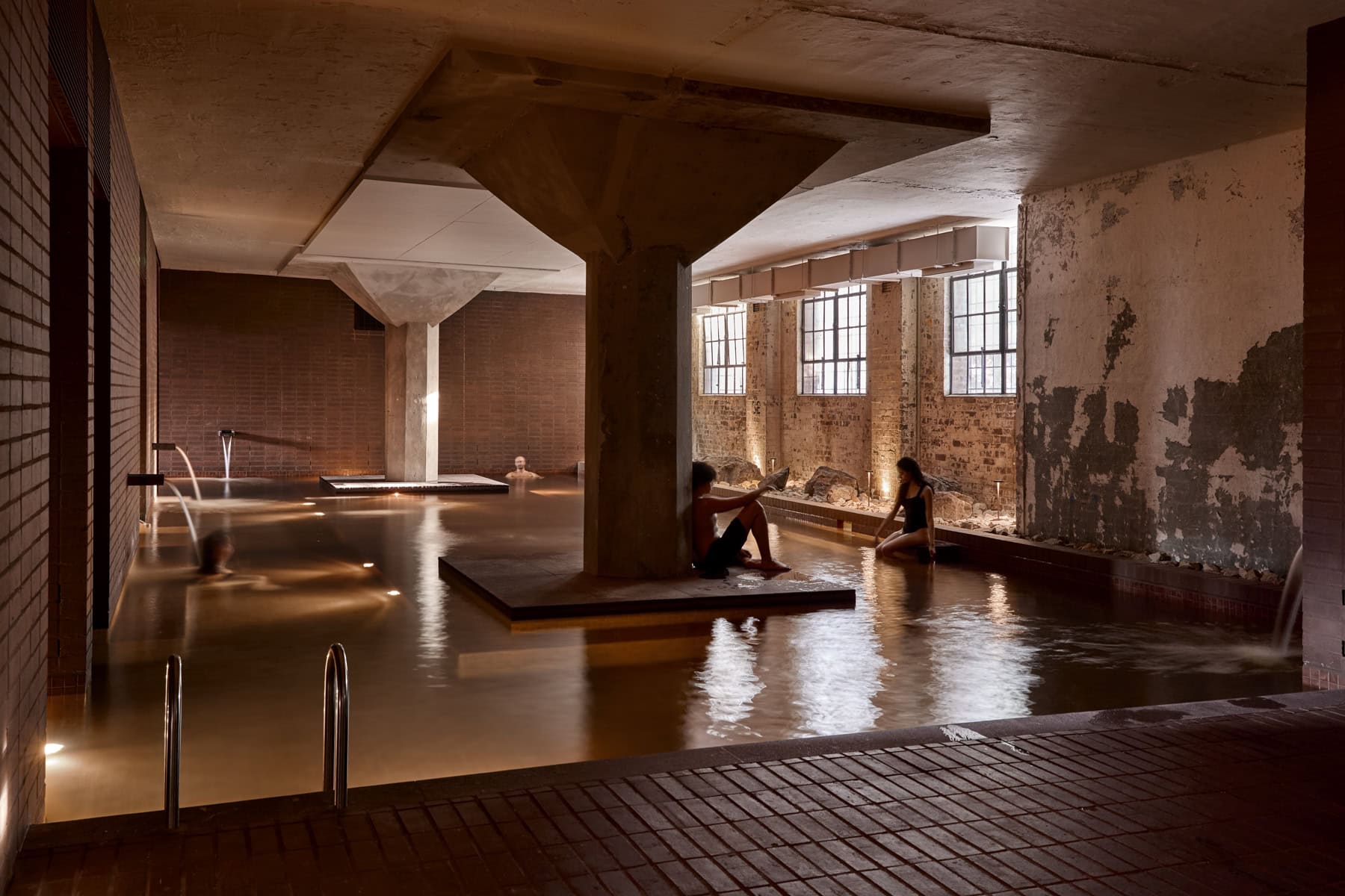 Large hot mineral pool among original concrete pillars and brickwork at Sense of Self bathhouse, Surry Hills Sydney