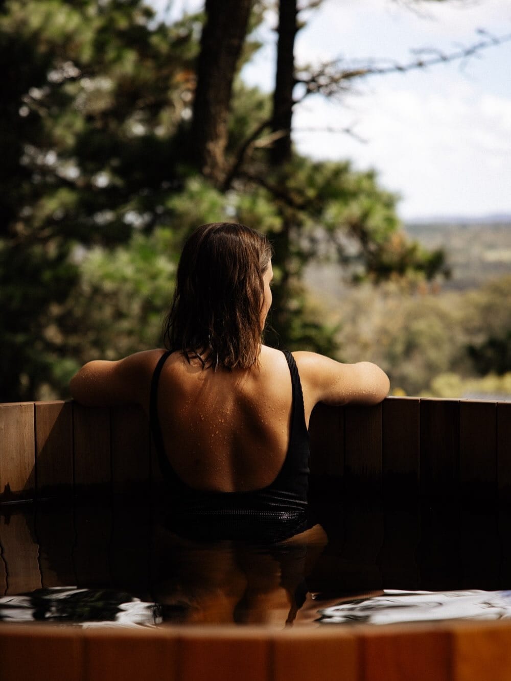 A woman in a black swimsuit with her back to the camera at Osborn House in the Southern Highlands.