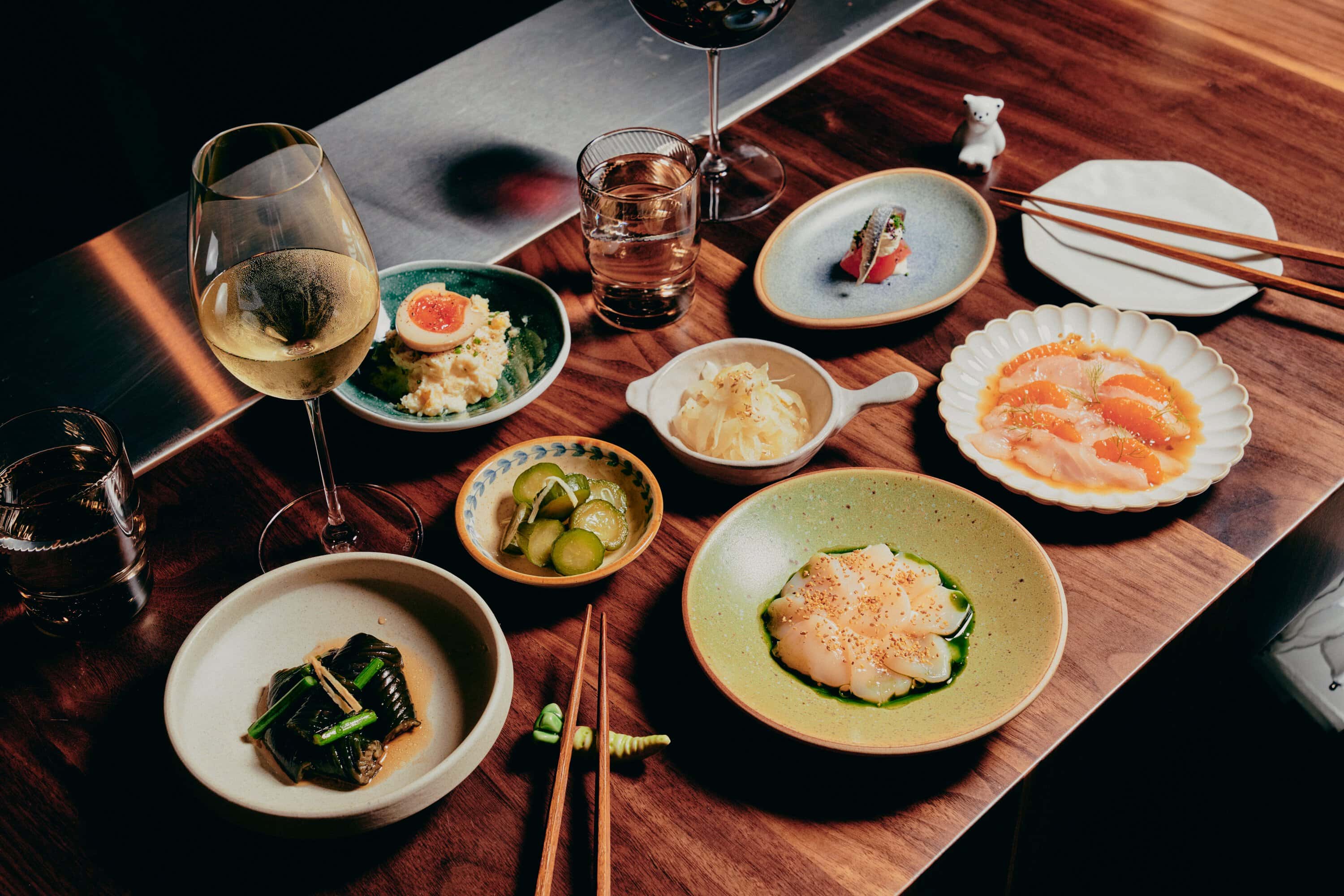 Overhead spread of Japanese small plates including sashimi, pickles and wine at Aenza Darlinghurst Sydney