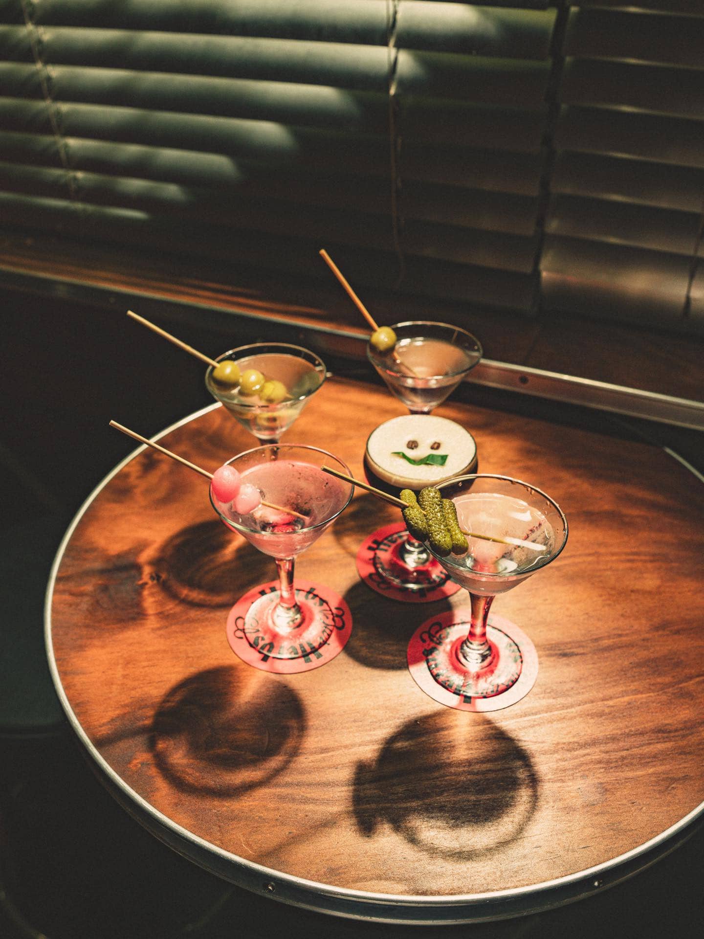 Martinis with olive, pickled onion and cornichon garnishes alongside an espresso martini at Bar Herbs, Sydney CBD