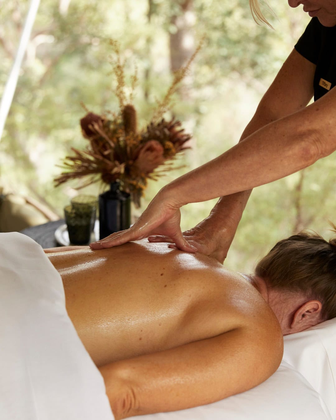 A woman receiving a massage at Spicers Sangoma with bushland visible in the background.
