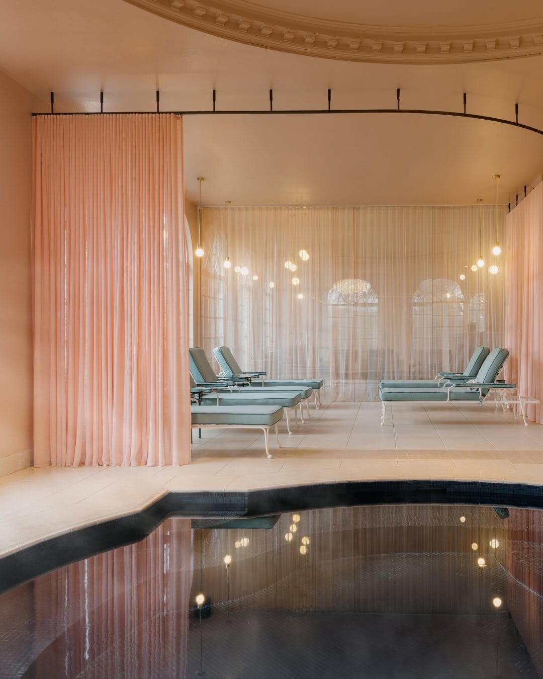 The pool at Ardour Milton Park, featuring a sheer pink curtain and teal sun loungers.