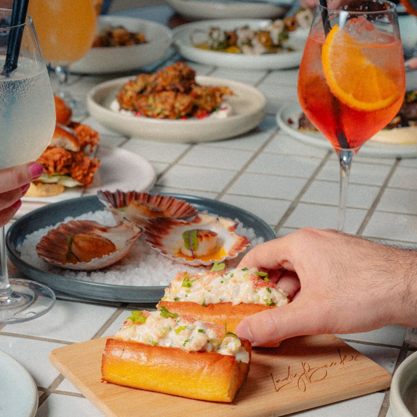 Someone picking up a lobster roll from a spread of food at Lady Banks Rooftop in Bankstown.