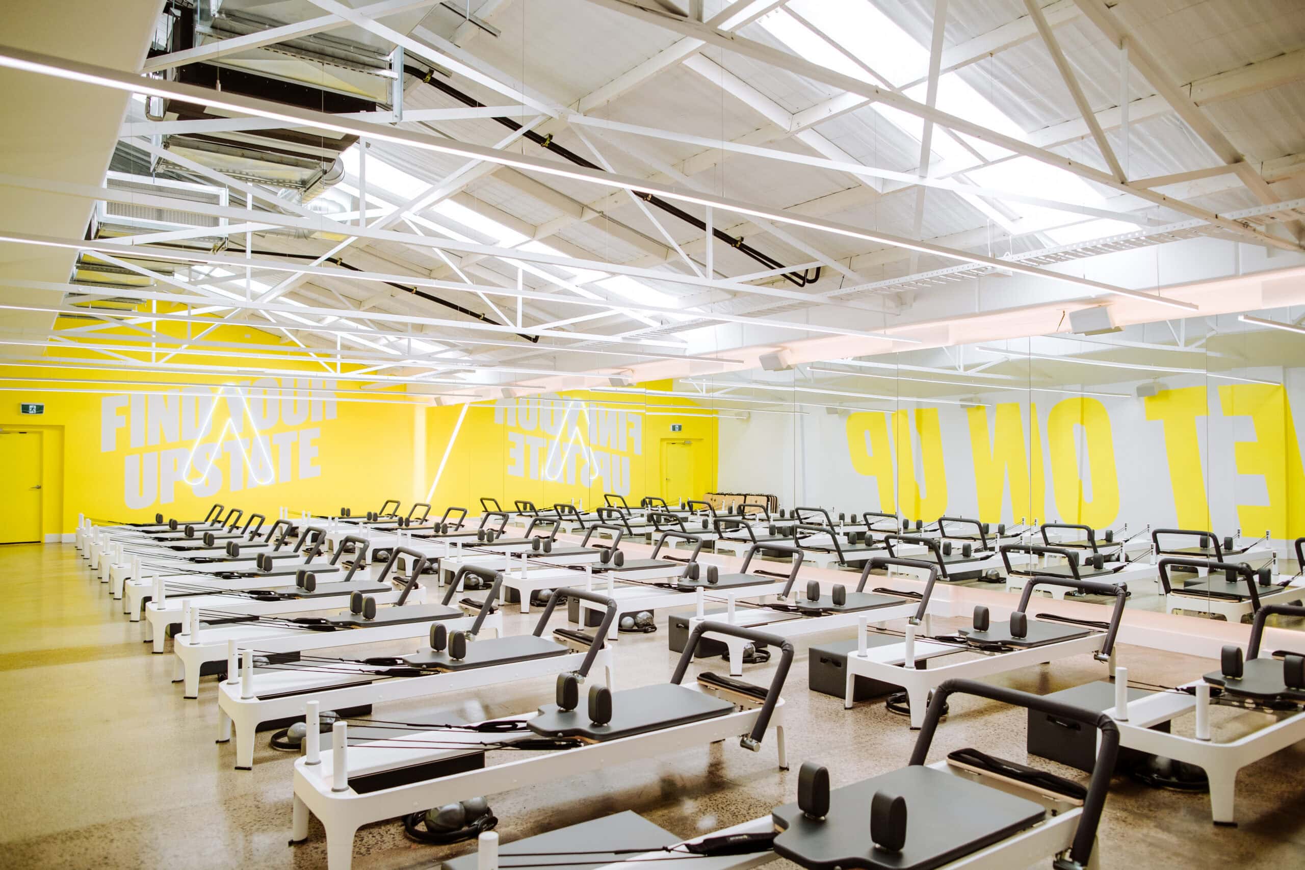 A yellow room full of reformer beds at Upstate Pilates in Brisbane.