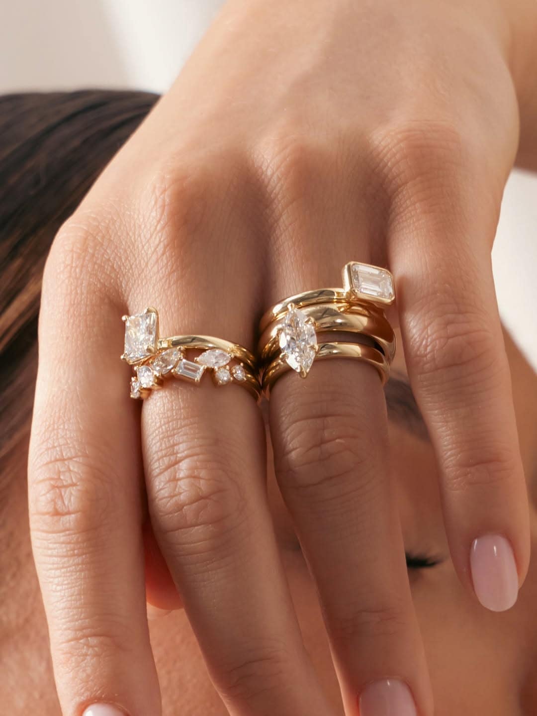 A hand model with multiple Claude & Me diamond rings on.