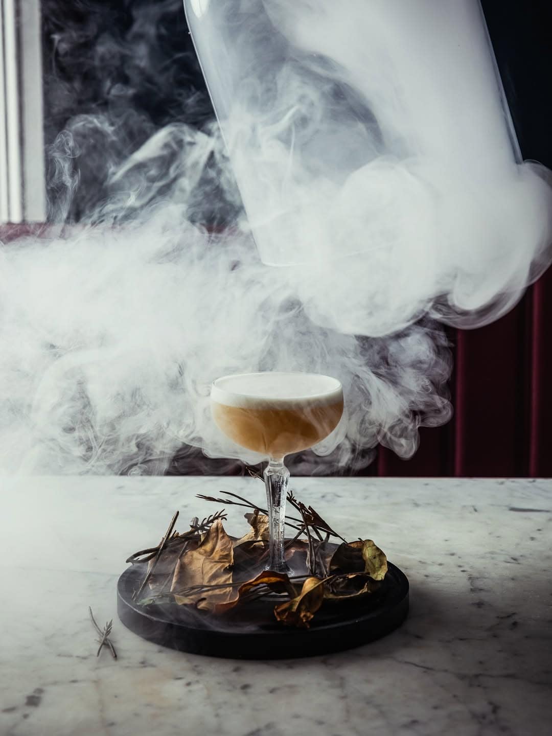 A smoking cocktail being unveiled from beneath a glass cloche at Gin Lane in Sydney.