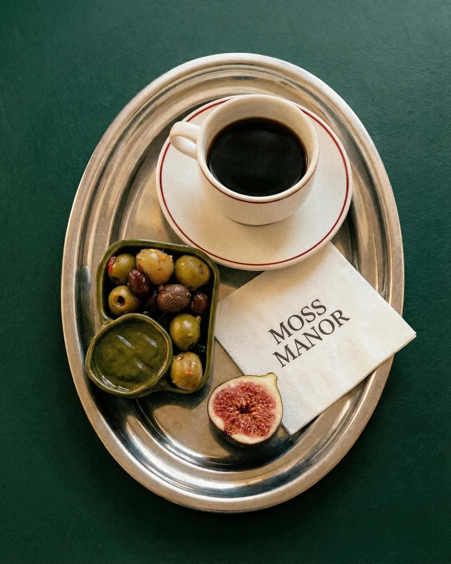 A silver tray with a coffee and olives at Moss Manor in Moss Vale.