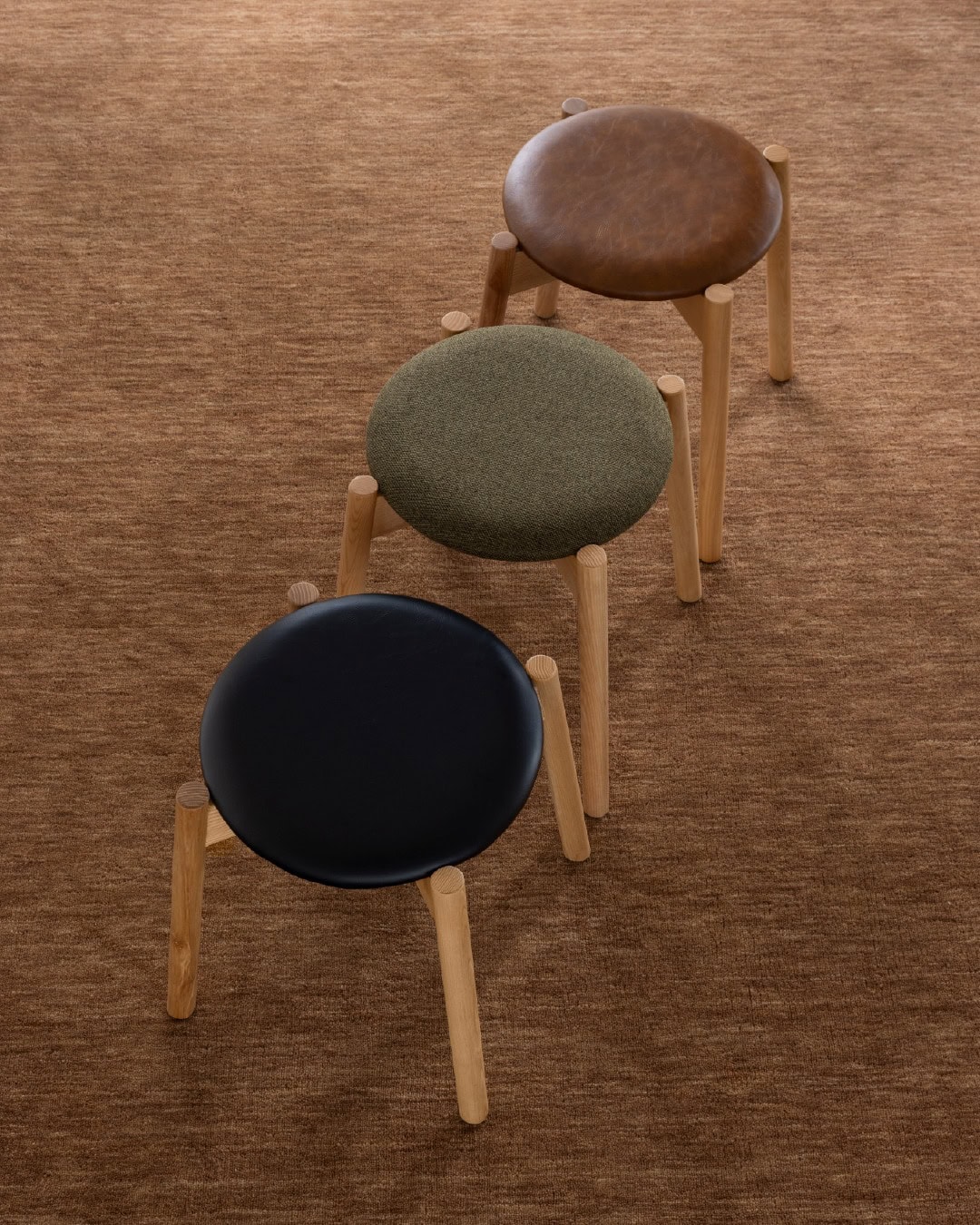 Three mid-century stools each with a different leather top from The Modern.