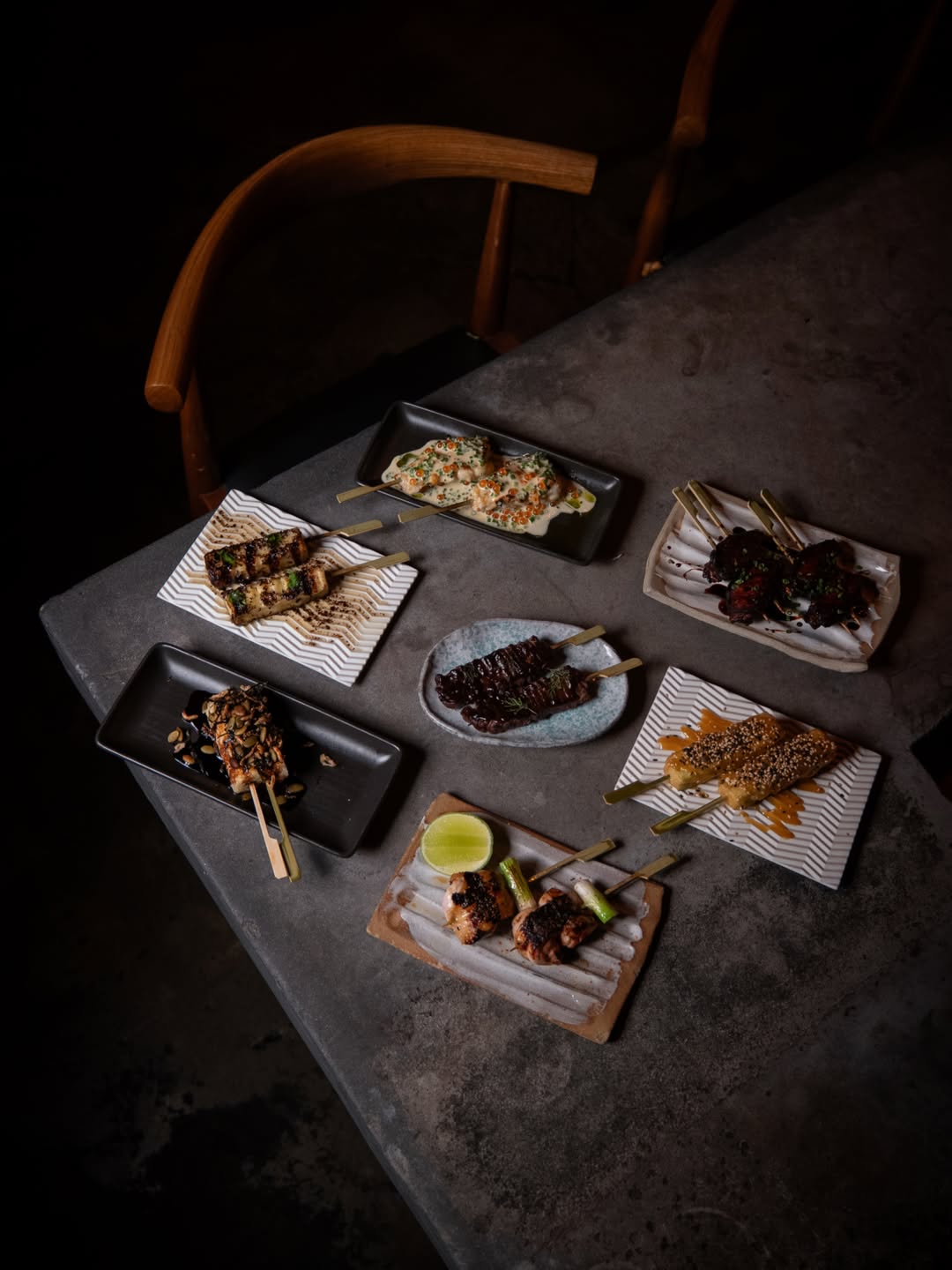 A concrete-style table topped with an assortment of grilled skewers, two to a plate, at Shoto in the Gold Coast.