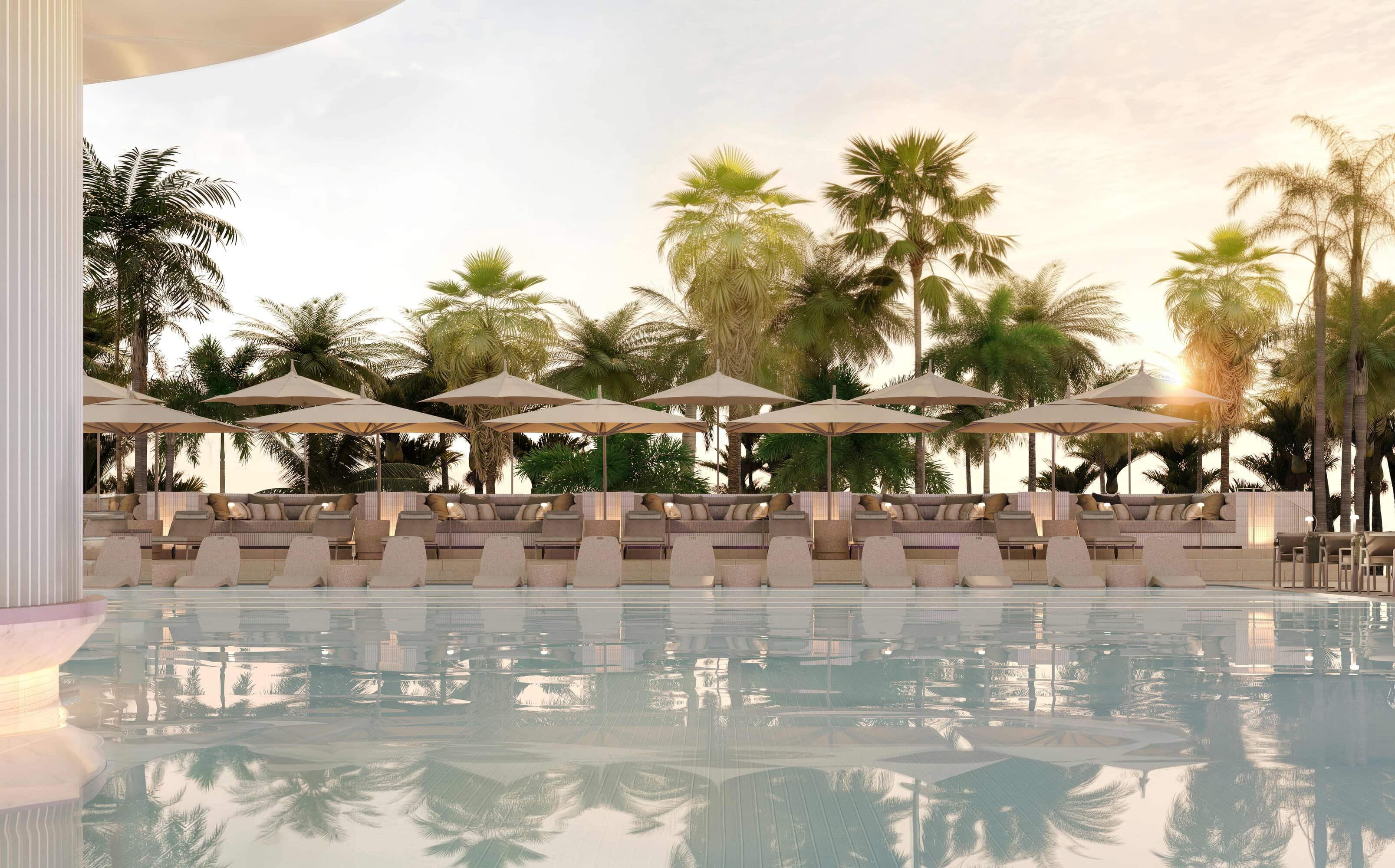 Andaz Gold Coast Resort pool deck at sunset with rows of cushioned lounge chairs and cream umbrellas along the water's edge, backed by tall palm trees under a soft golden sky.