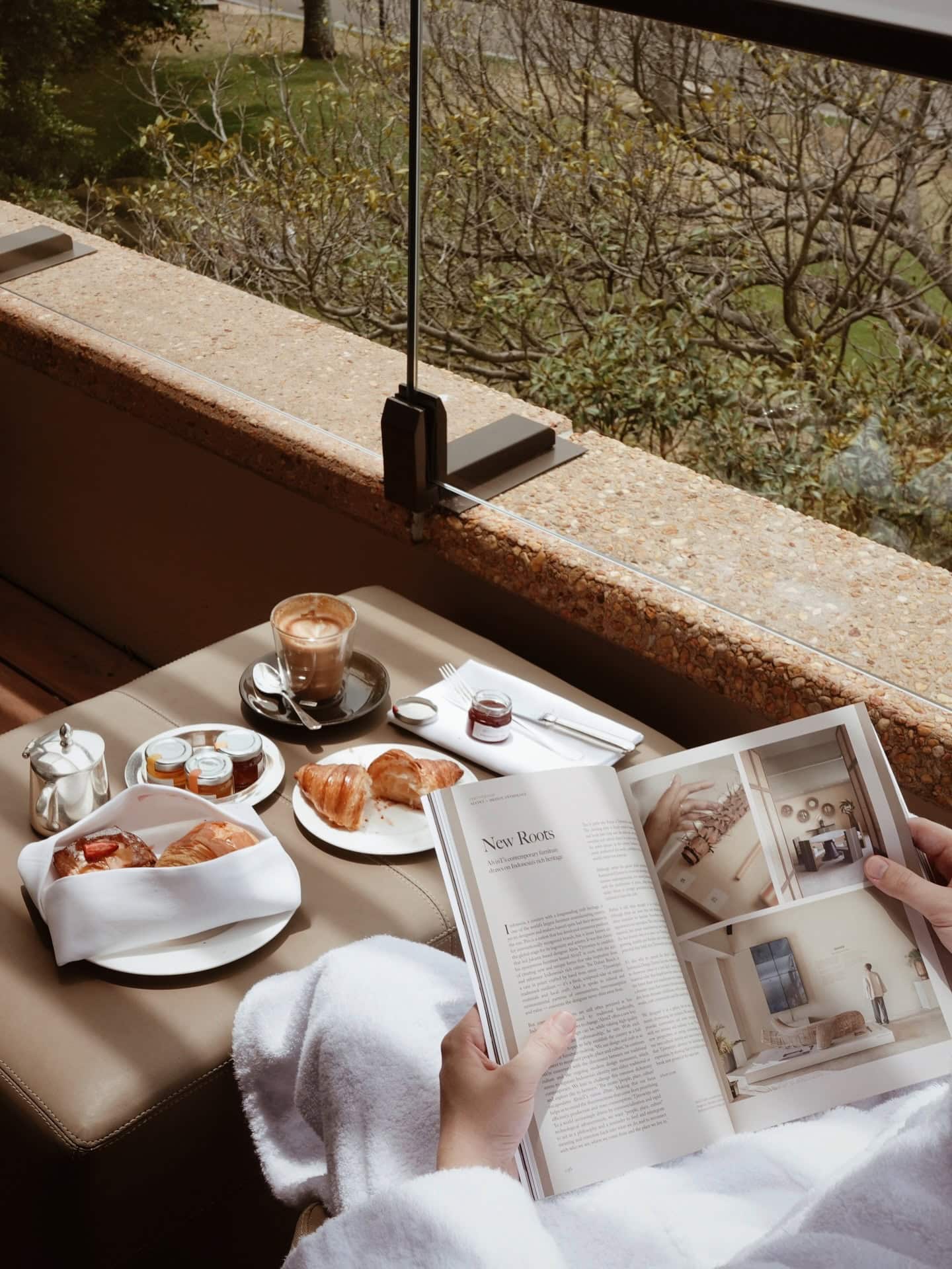 Someone reading a magazine and enjoying breakfast by the window at Park Hyatt Sydney.