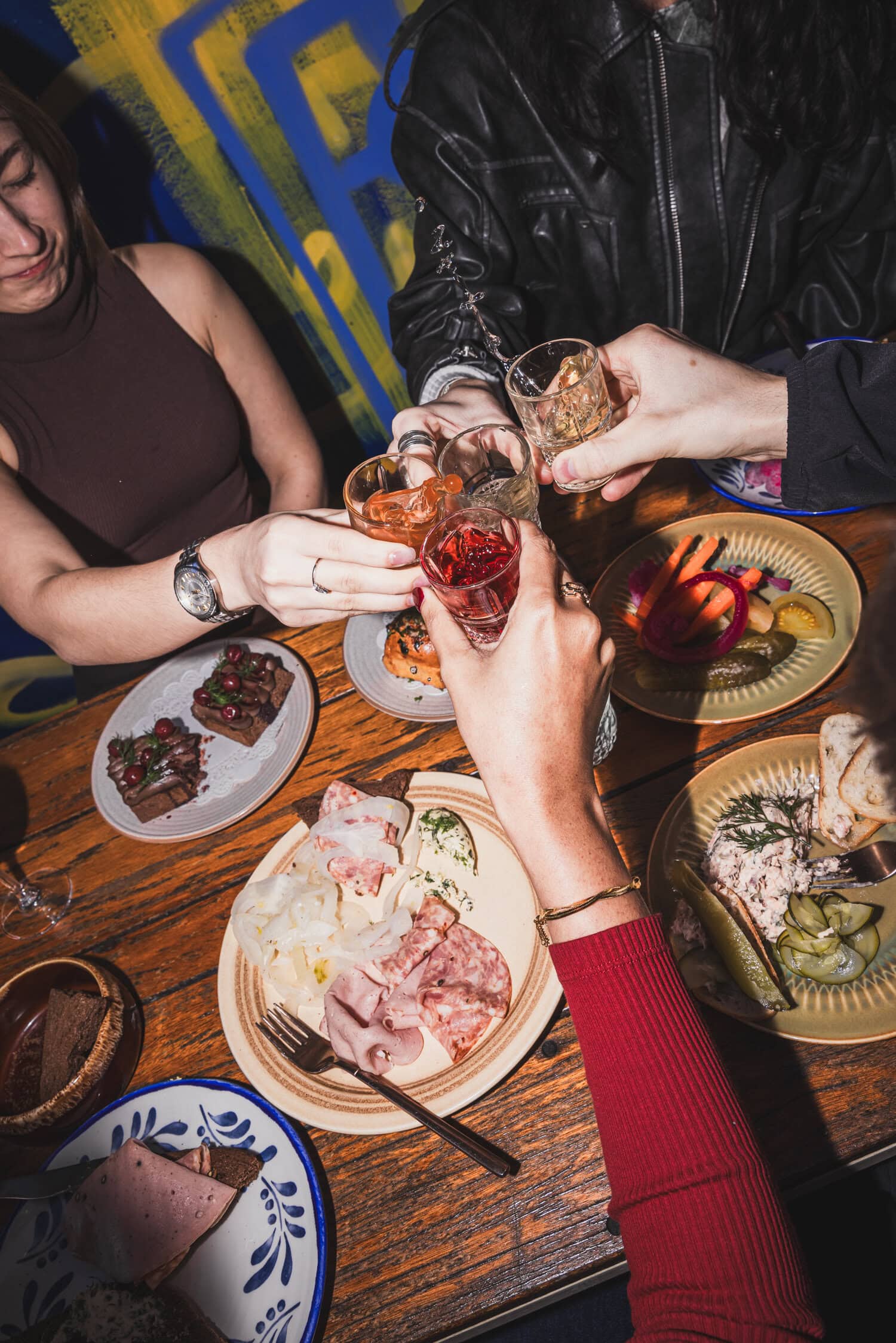 Group toasting shots over charcuterie and pickles spread at Kyiv Social Chippendale Sydney