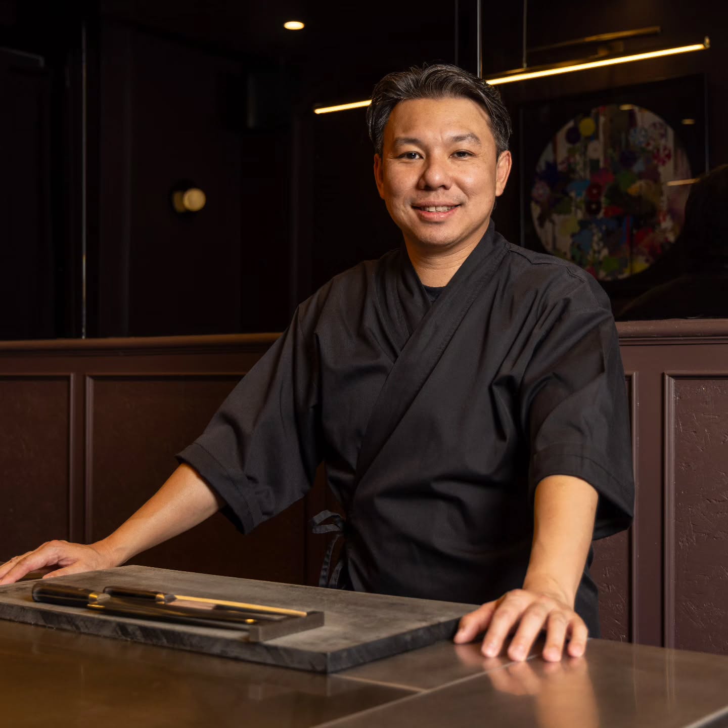 A portrait of Chef Ha Chuen Wai behind the omakase counter.