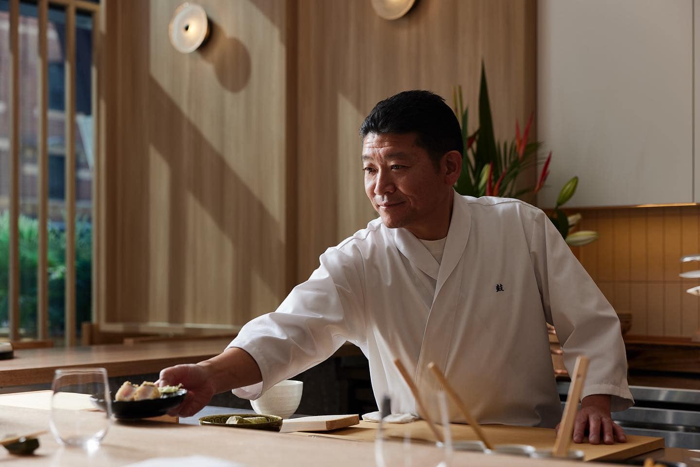 Chef Jun leaning across the omakase counter at Tsuzmi in Barangaroo.