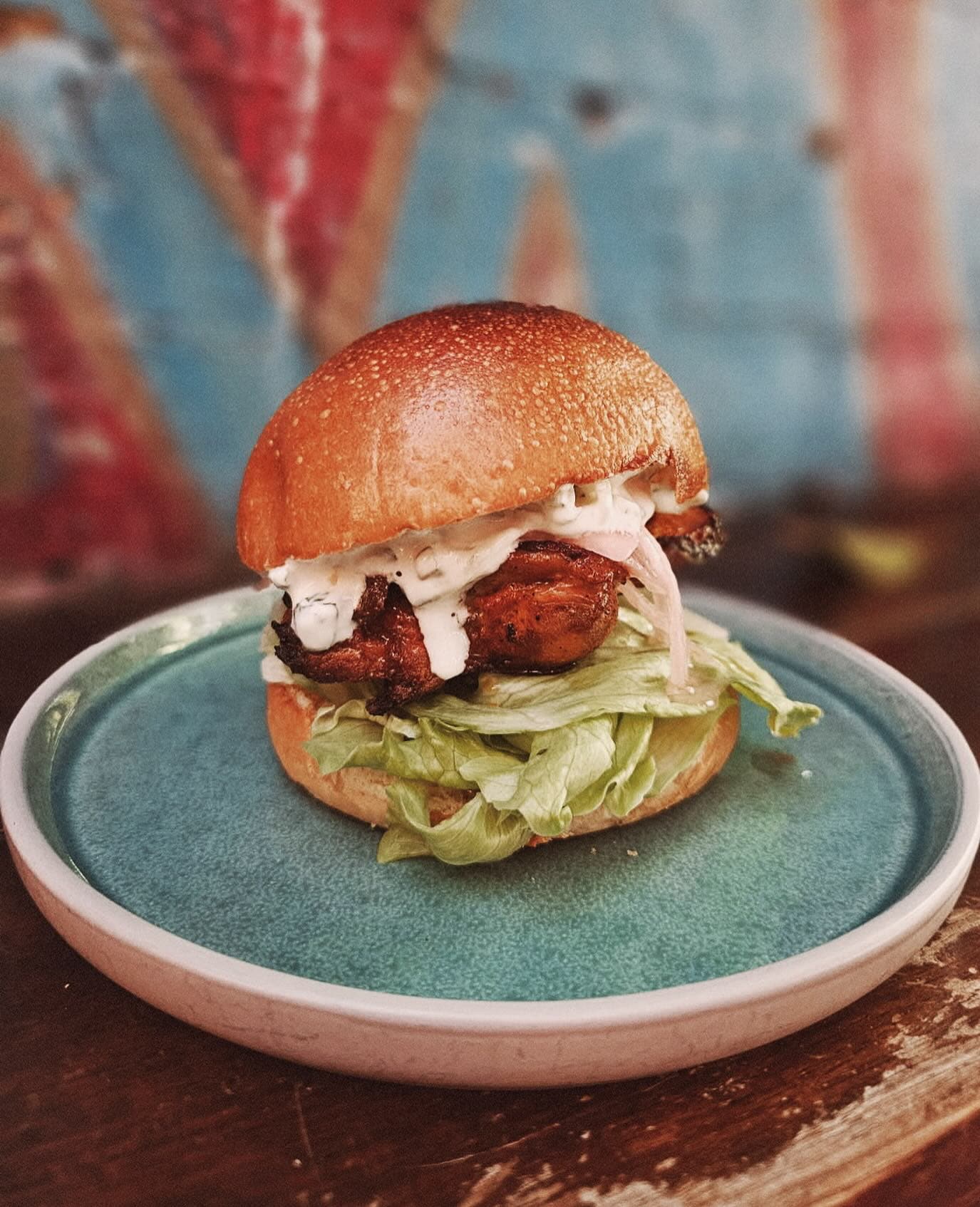 A chicken burger on a blue plate at Sappho in Glebe.