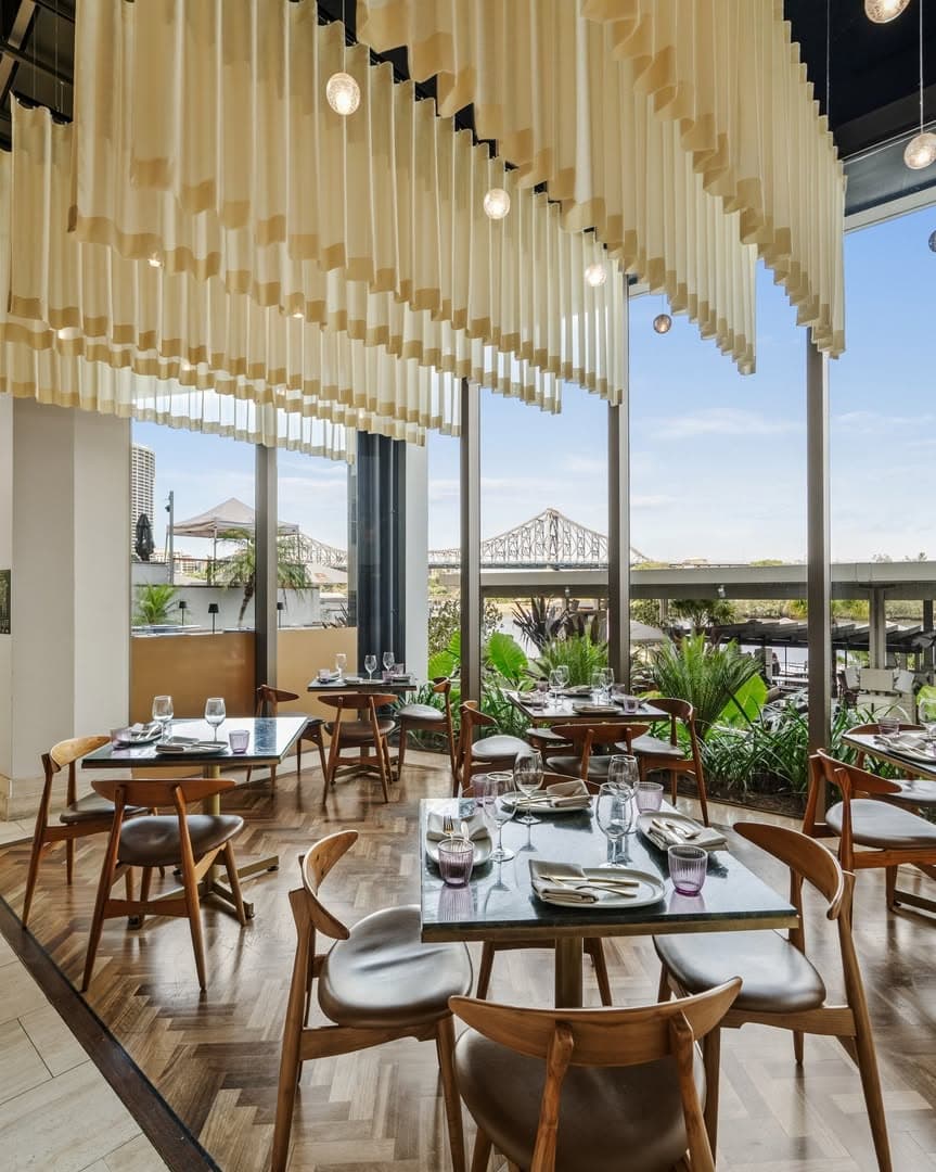 The pared-back dining room at Babylon Brisbane featuring floor-to-ceiling windows and views out across the Brisbane River.