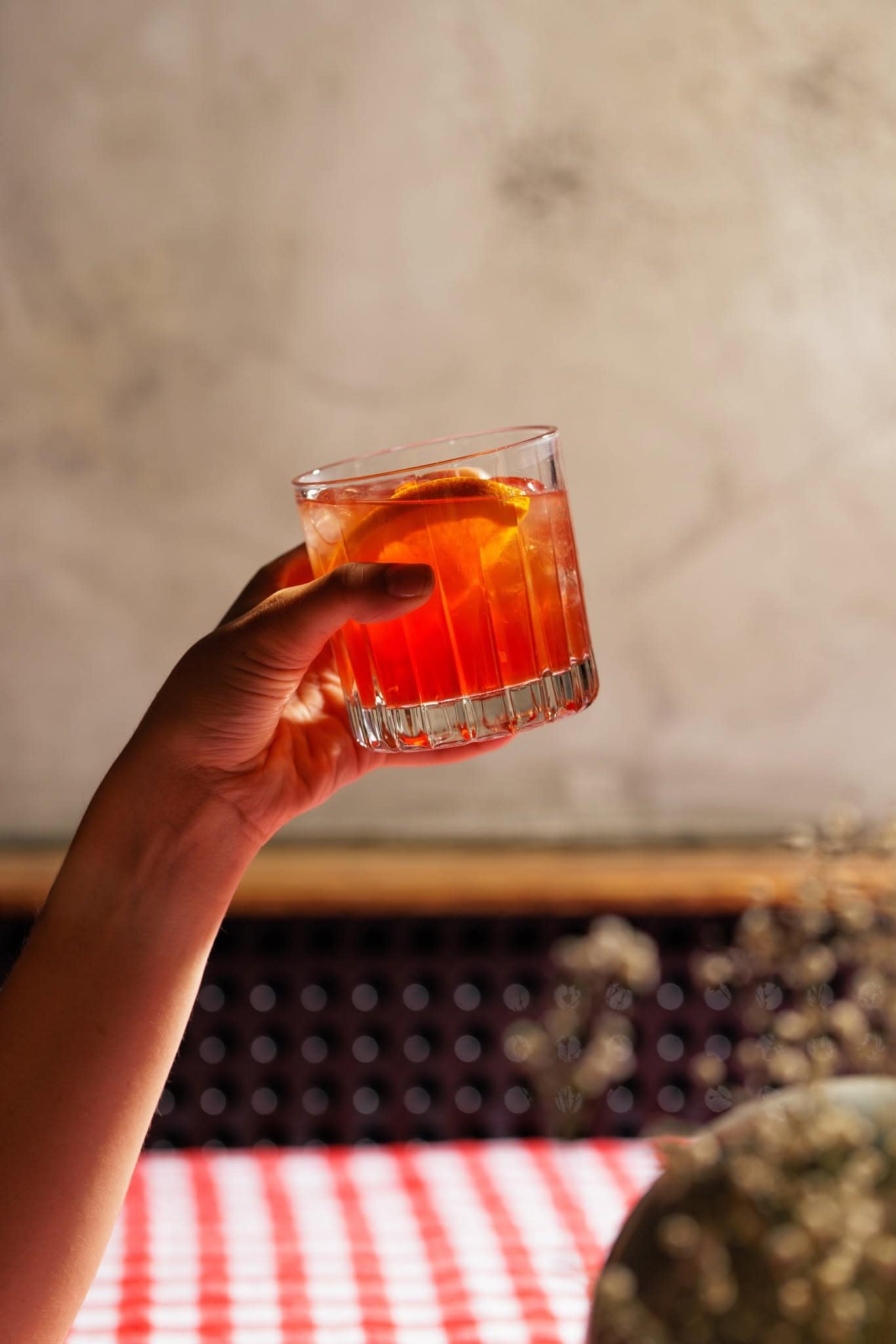 Hand holding a Negroni garnished with citrus inside Holly’s in Ringwood.