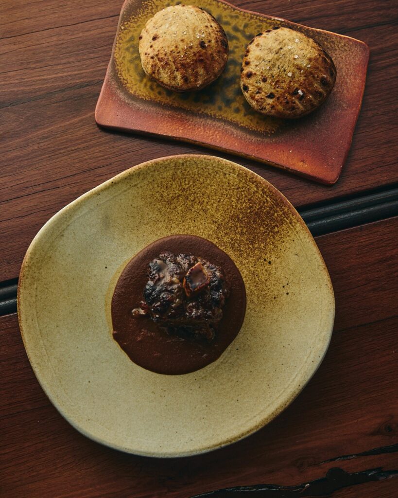A ceramic dish of Kangaroo tail and two fire-cooked breads at Firedoor in Surry Hills.