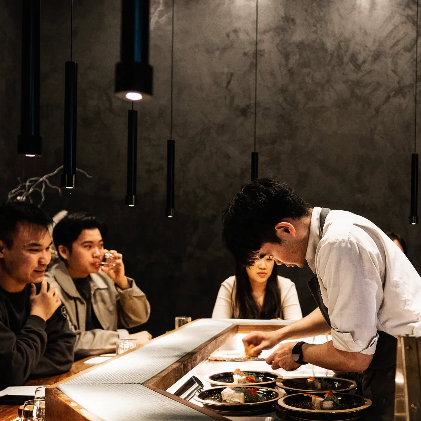 A Haco omakase chef preparing plates for counter diners.