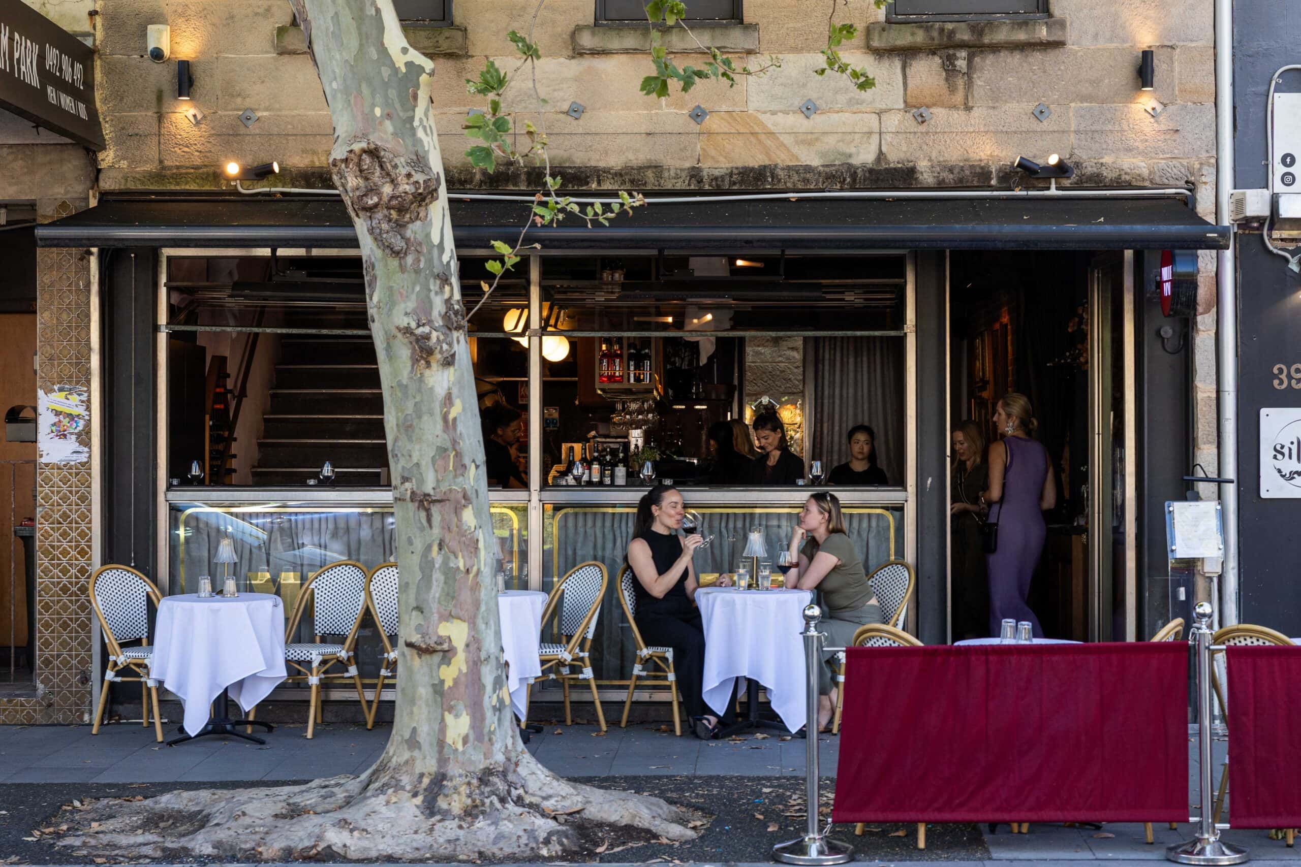 Outdoor footpath dining with bistro chairs and white tablecloths at Mille Vini wine bar, Surry Hills Sydney