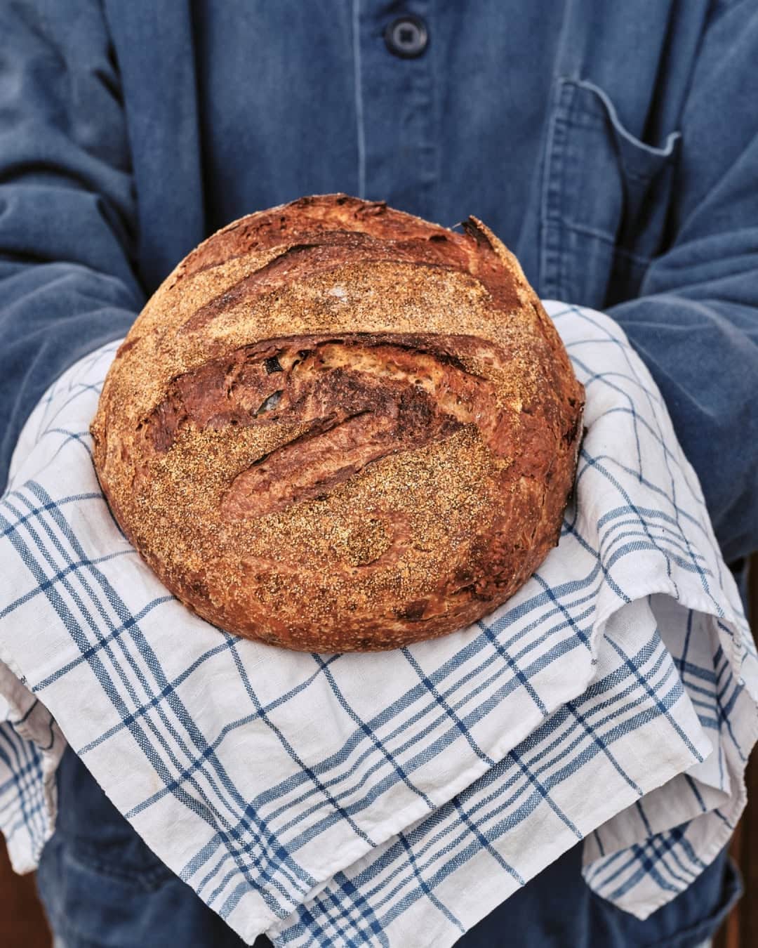 Someone holding a circular loaf of sourdough in a tea towel at Lagom in Burrill Lake.