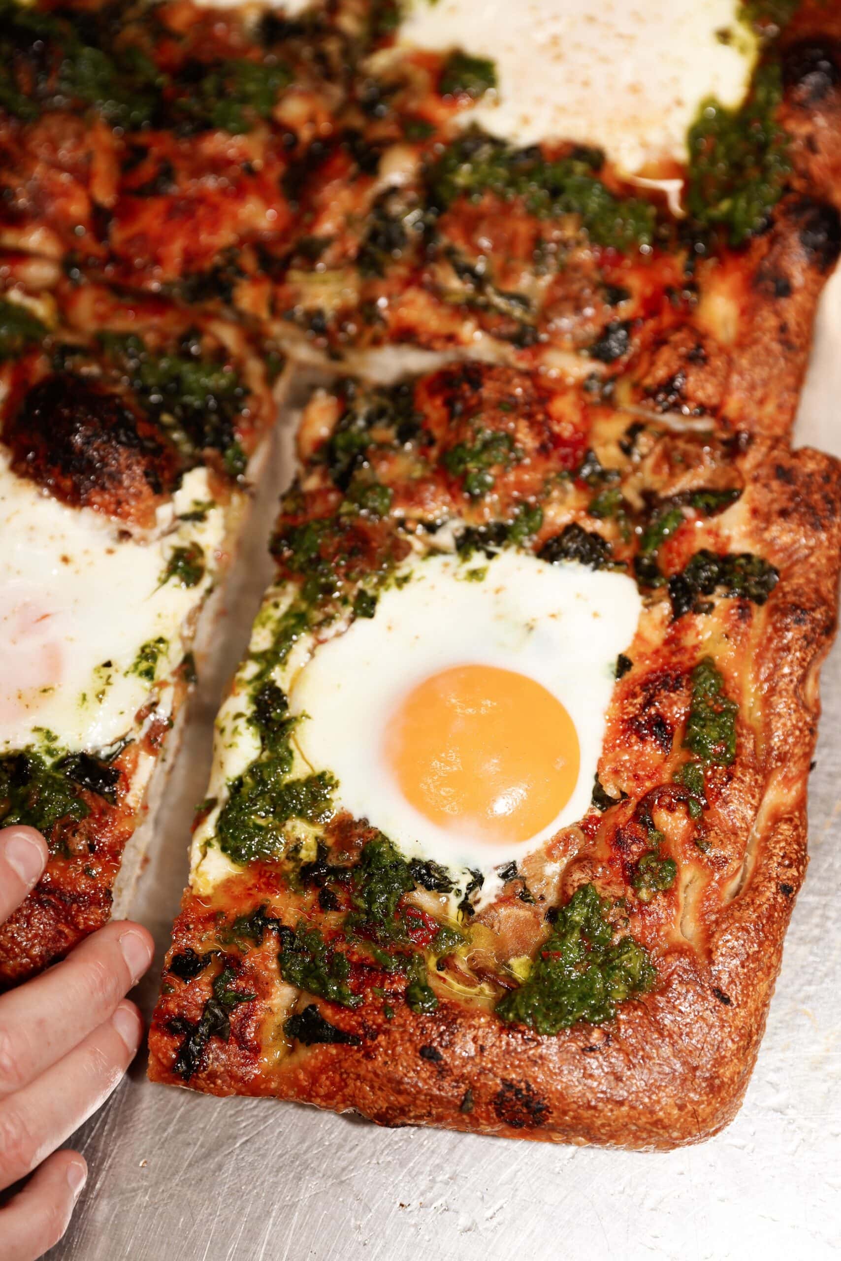 Slice of Sonoma sourdough pizza topped with herb sauce, cheese and a fried egg, Alexandria, Sydney