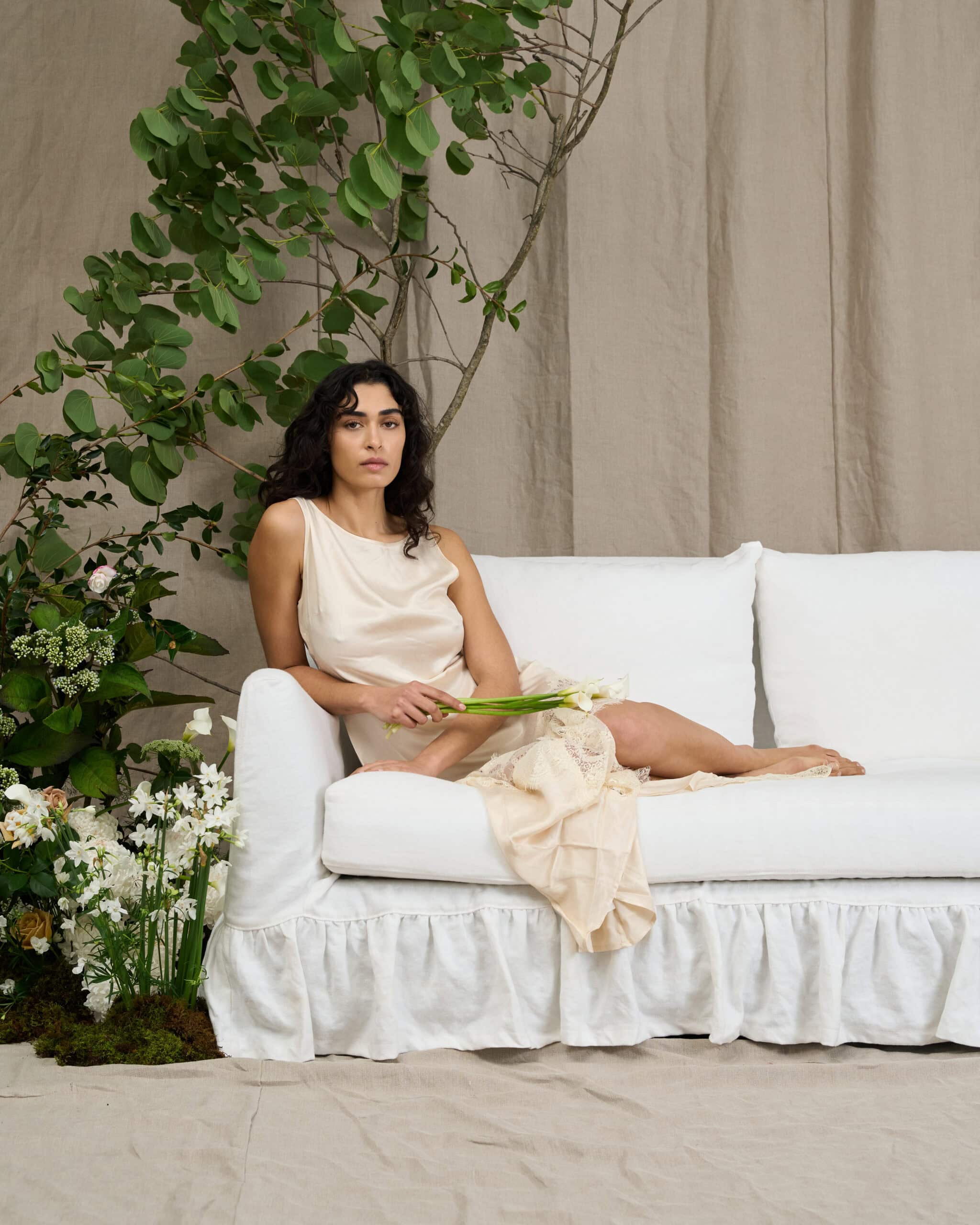 Model seated on the Maisie sofa in White from Crafted, styled with florals