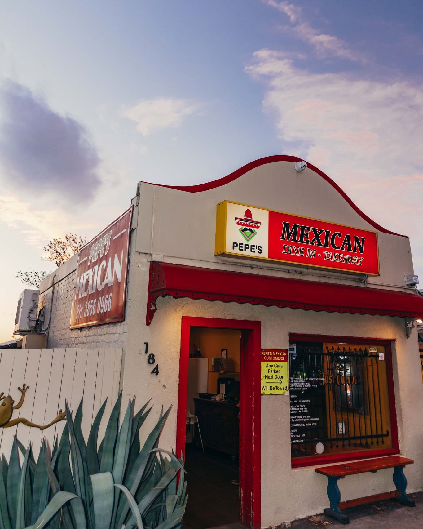 The exterior view of Pepe's Newmarket, with a concrete facade and red doorway.