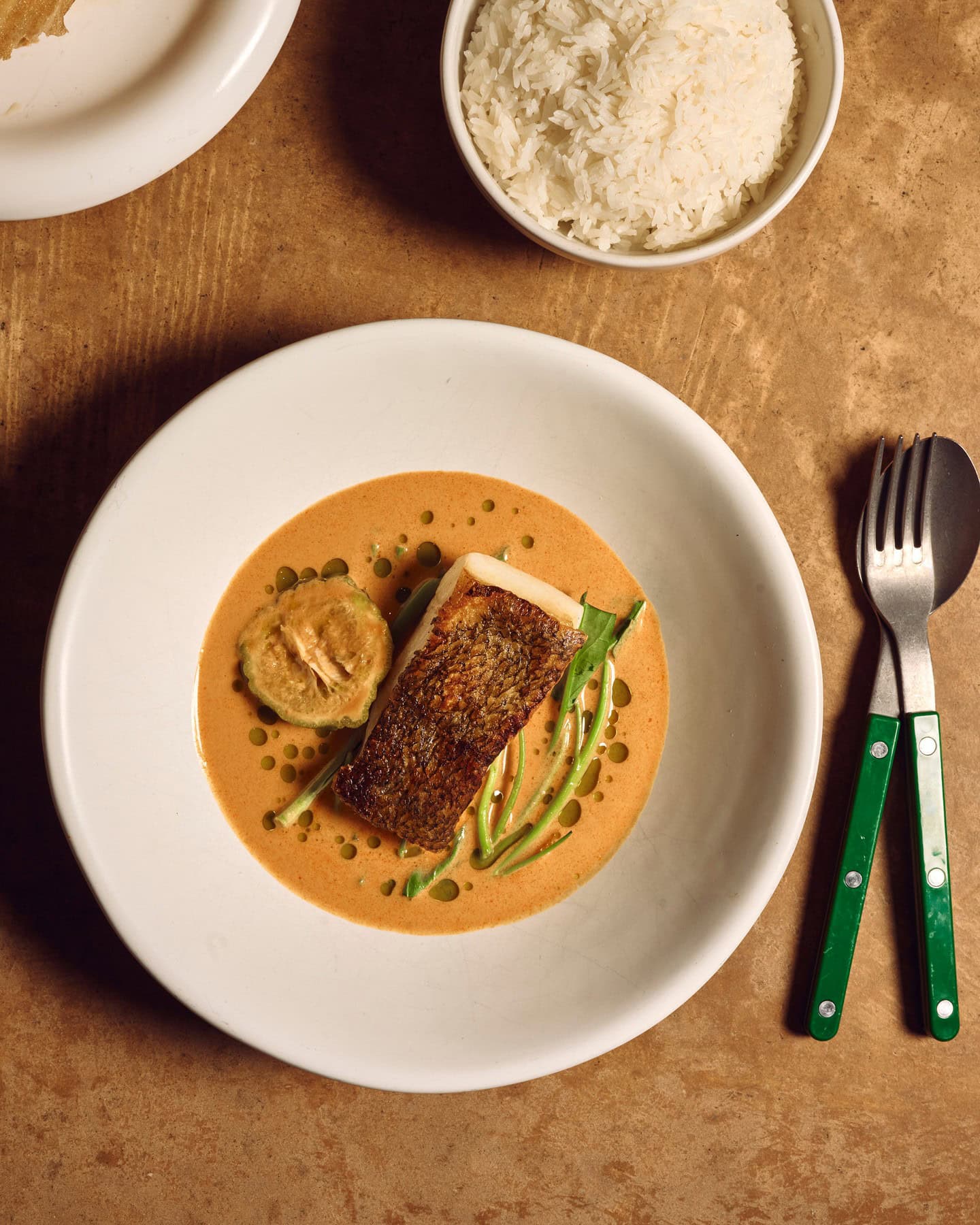 A bowl of tamarind curry topped with a fillet of crispy skin toothfish