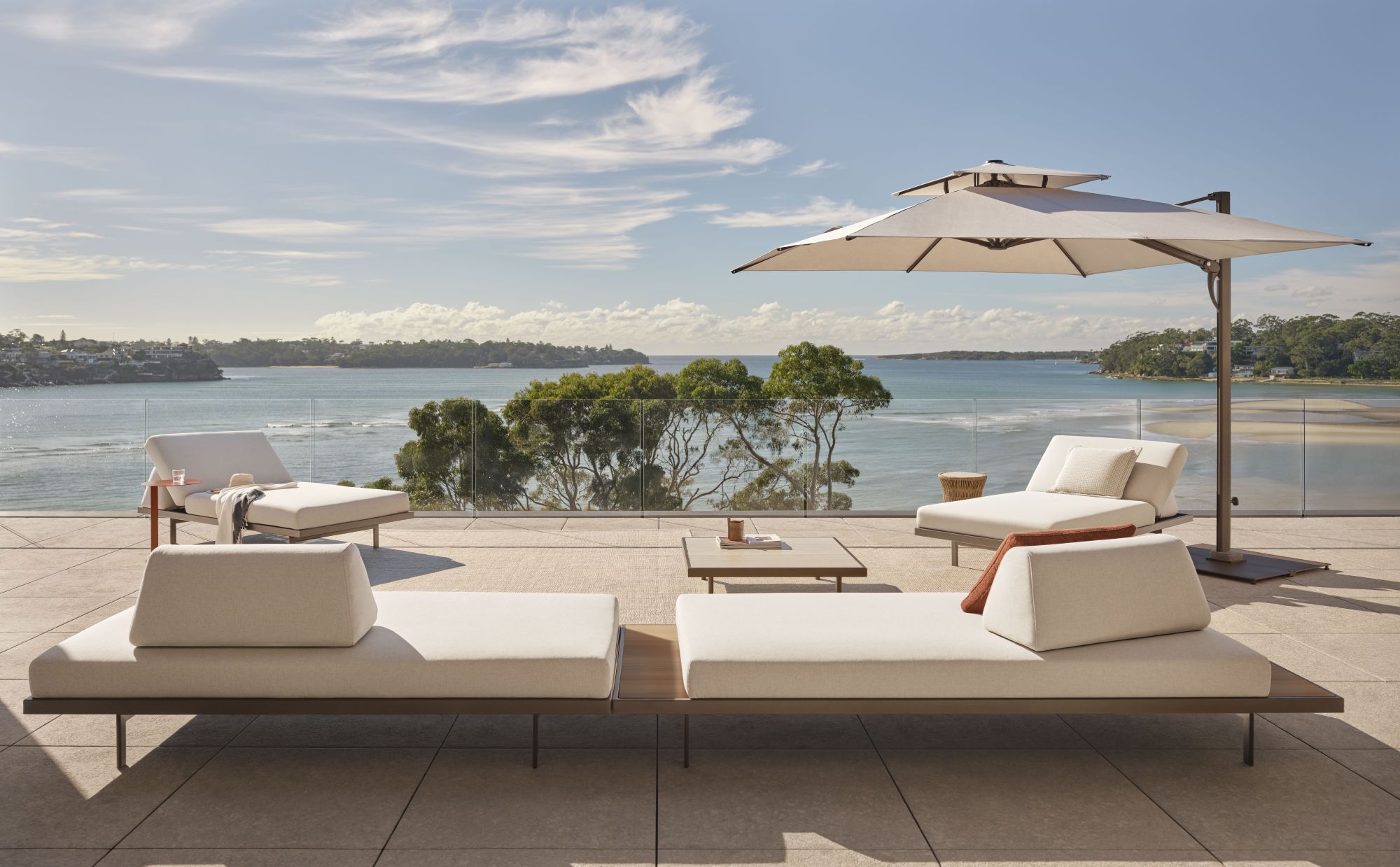 Plateau outdoor 2-seater daybeds by King Living styled on a terrace overlooking the ocean