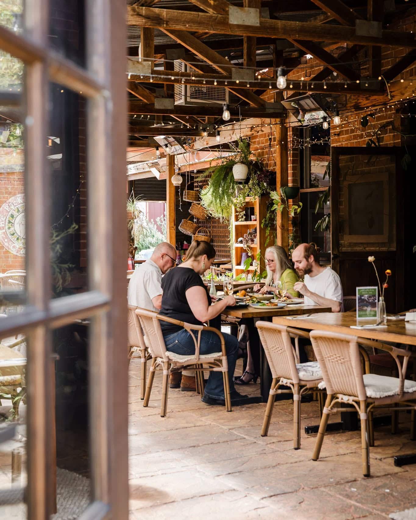 Covered courtyard dining at Pickled Sisters in Rutherglen, with timber beams, hanging plants and guests enjoying lunch.