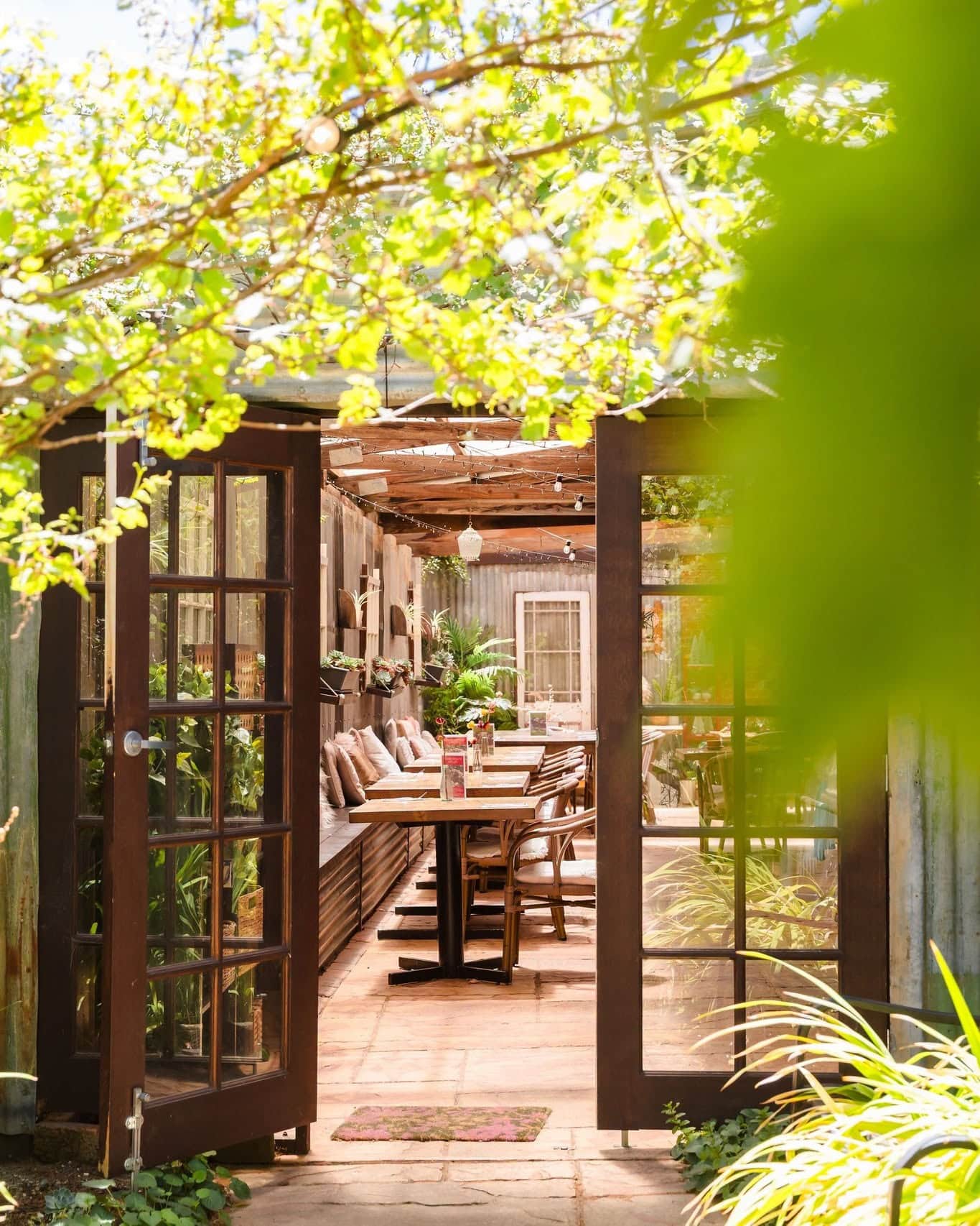 Garden courtyard entrance to Pickled Sisters restaurant in Rutherglen, surrounded by greenery and outdoor dining tables.