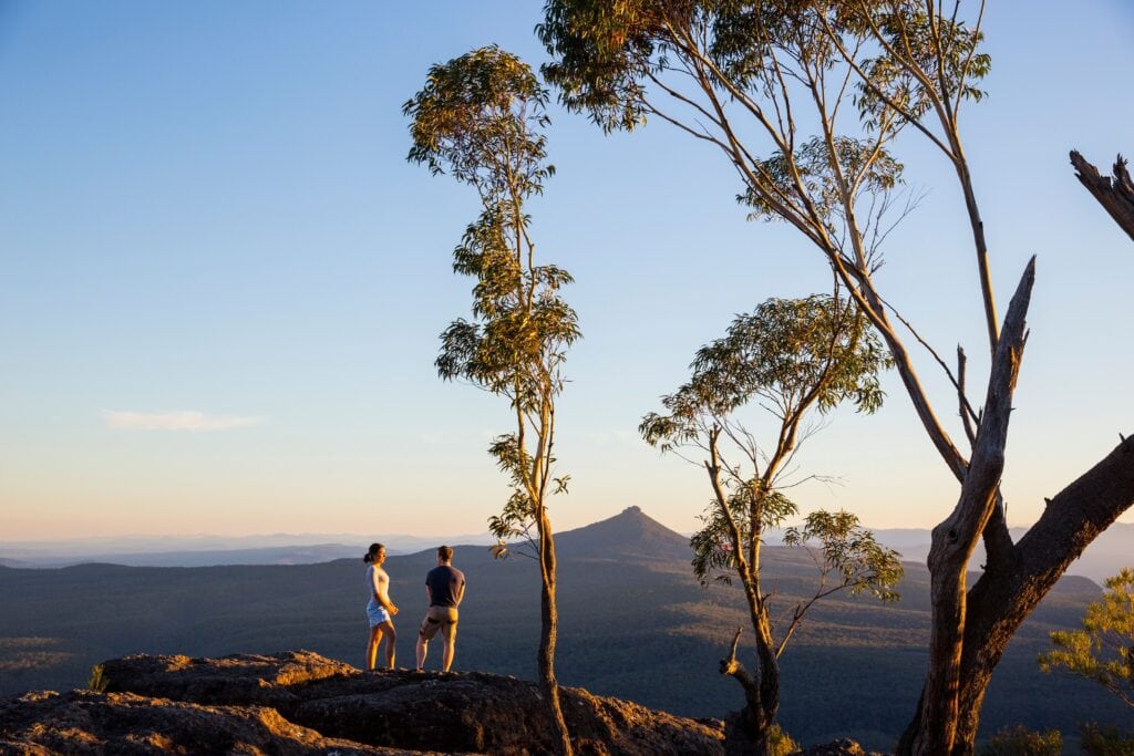Couple enjoying panoramic views across to Pigeon House Mountain (Aboriginal: Didthul) in Morton National Park.