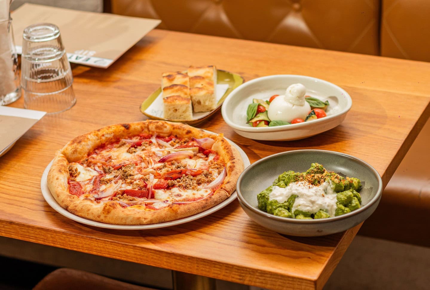 Pizza, salad, and bread served on a wooden table at Corbett & Claude.