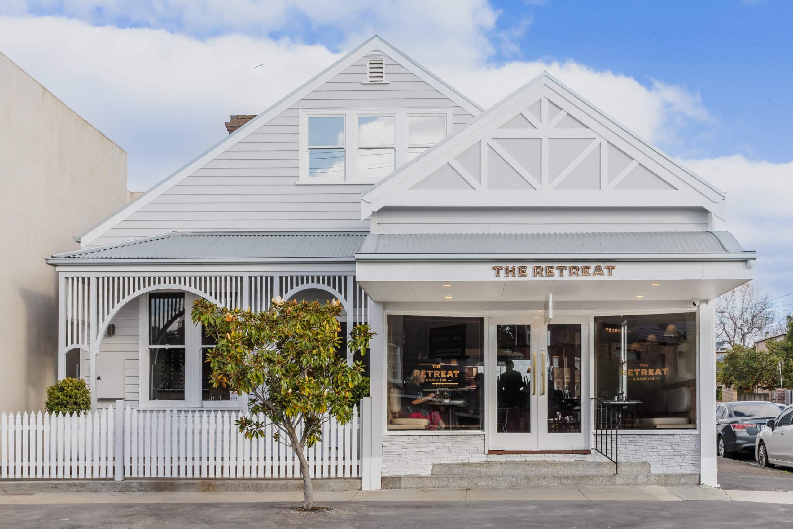 Exterior of The Retreat Restaurant & Bar in Geelong, set inside a restored white weatherboard building with a welcoming street frontage.