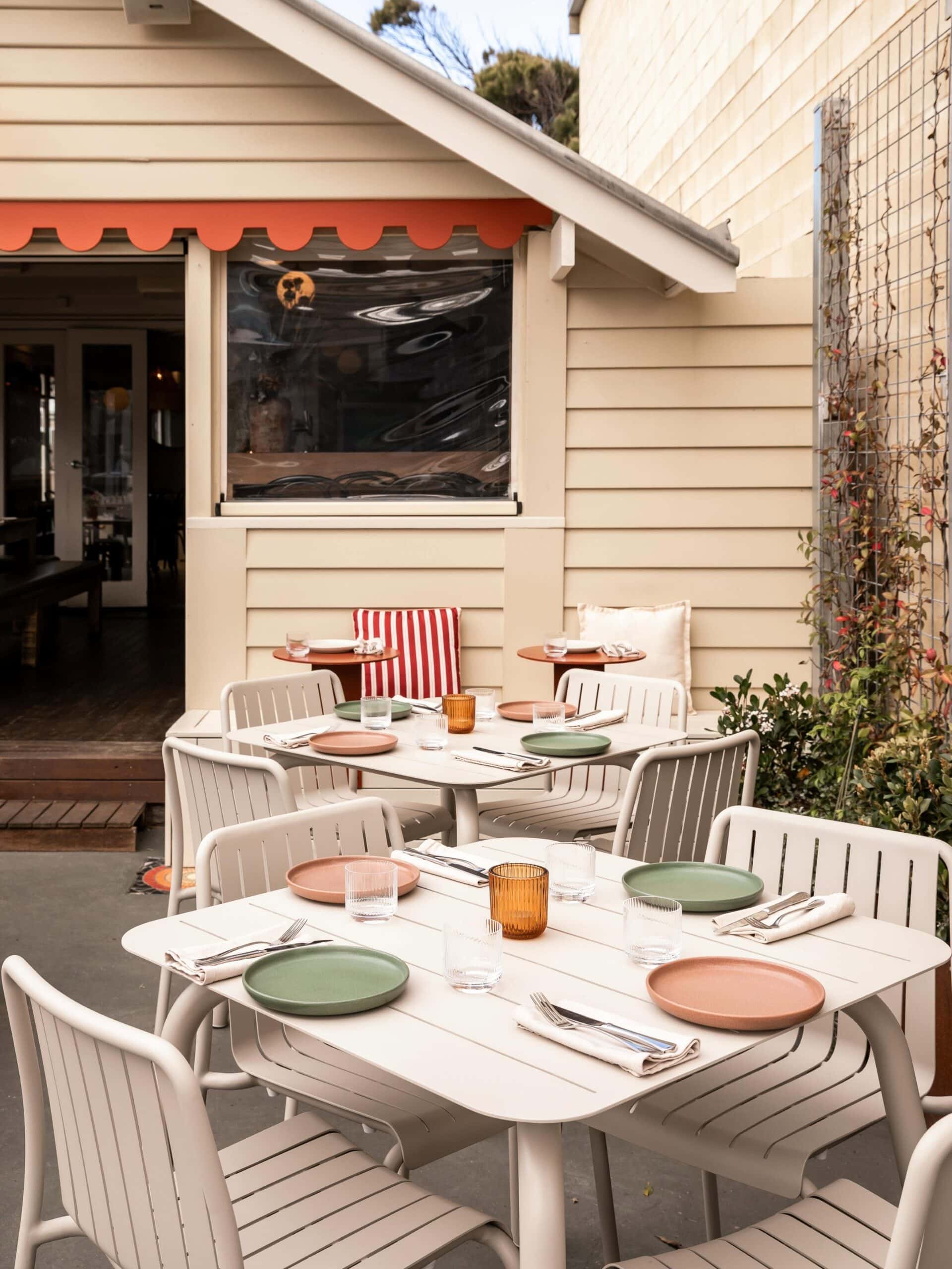 Outdoor courtyard dining at Tommy Gunn’s in Barwon Heads, with pastel tableware and relaxed coastal restaurant seating.