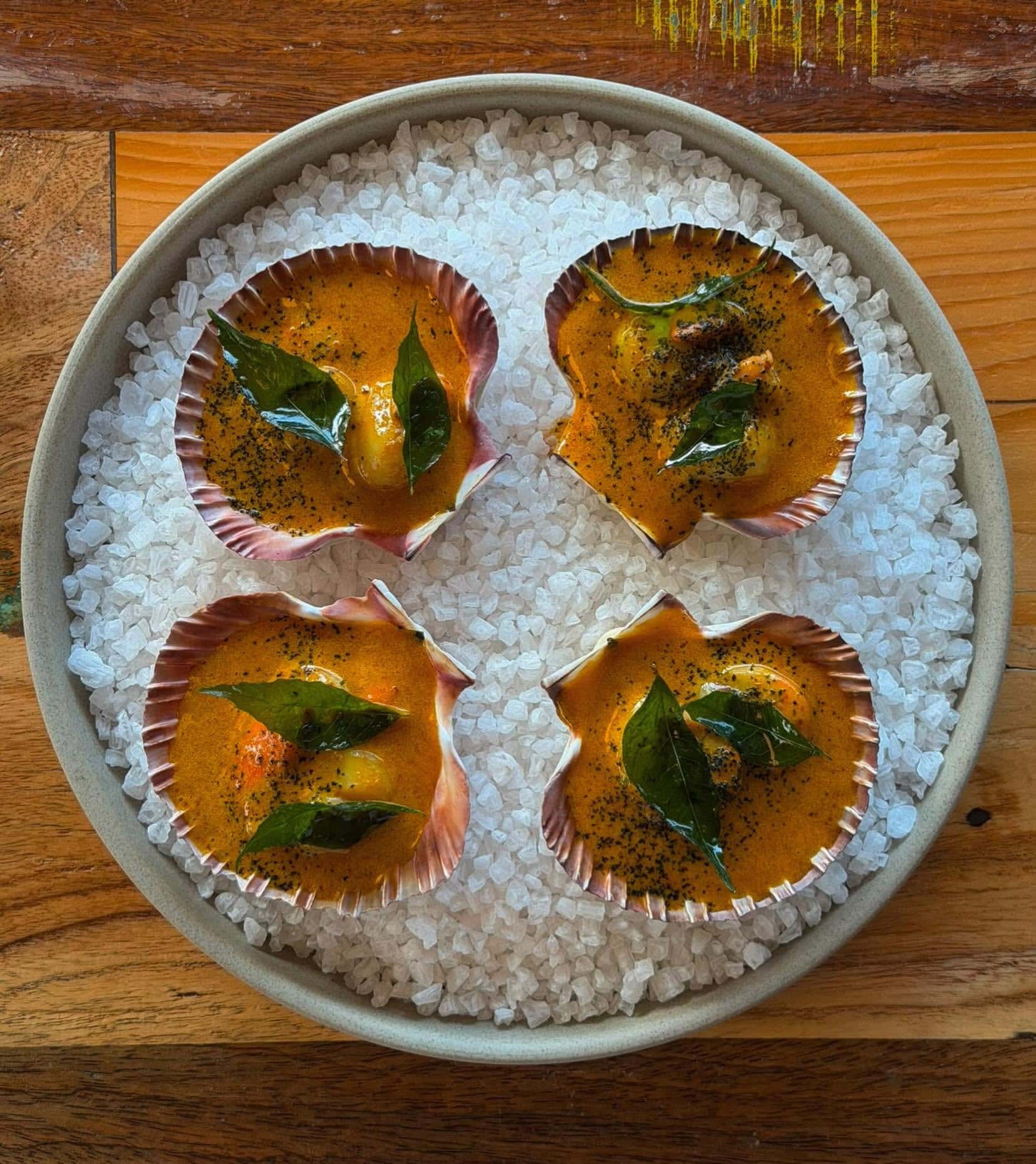 Scallops served in the shell with rich sauce and curry leaves at Tommy Gunn’s restaurant in Barwon Heads.