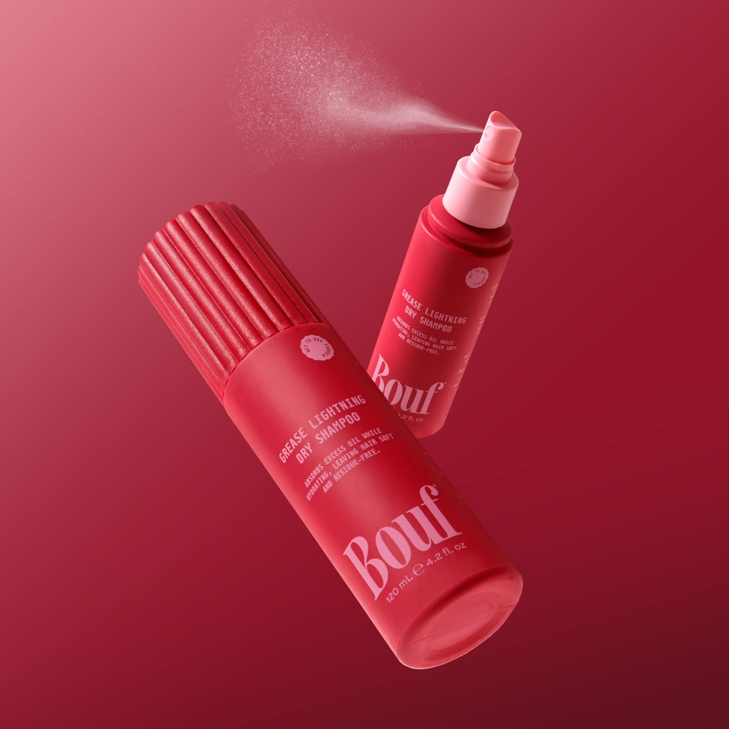 Bouf Grease Lightning Dry Shampoo bottles spraying against a deep red background