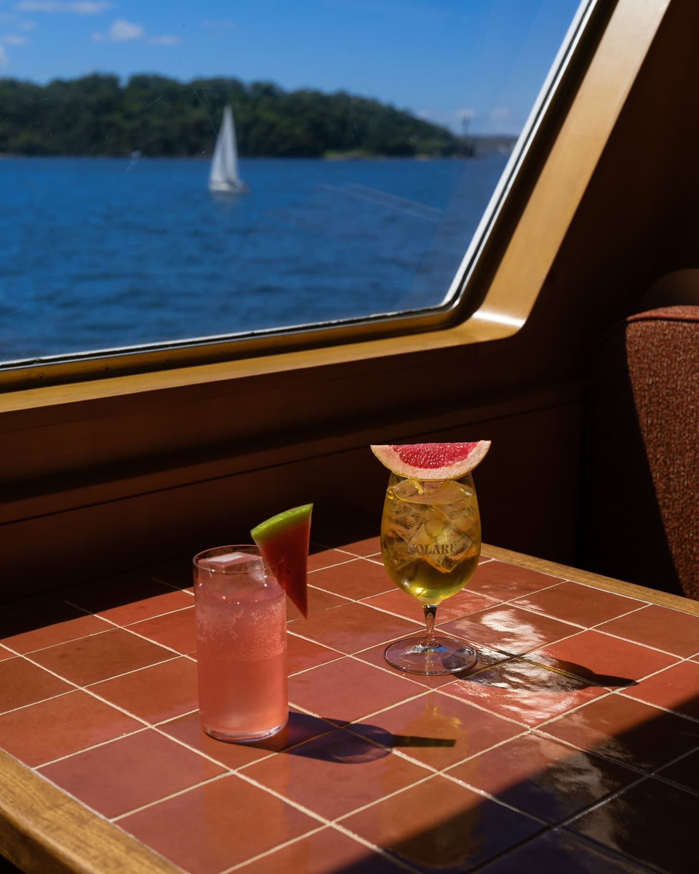 Cocktails on a tiled table aboard Solare with Sydney Harbour views through the window