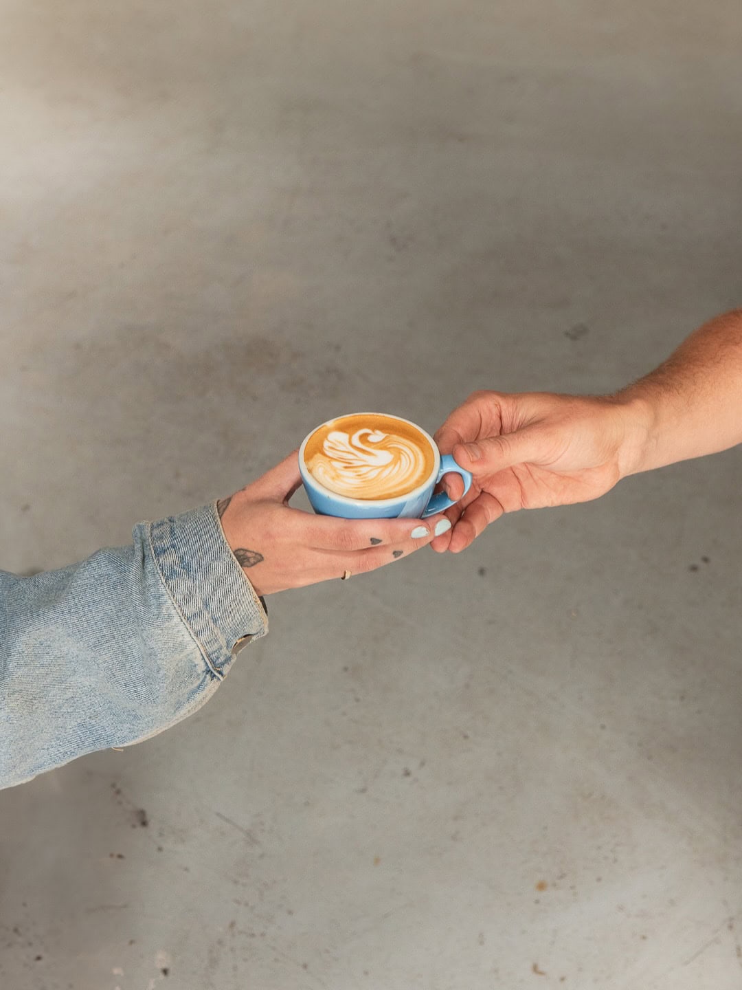 Someone passing a coffee to another person at Moonshine Coffee in Federal.