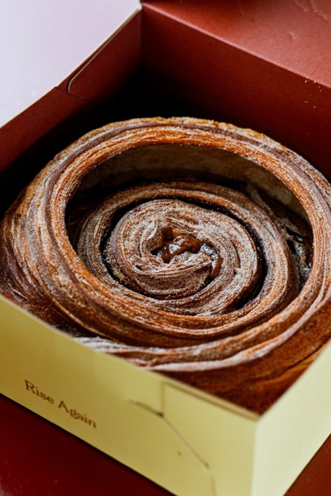 Cake-sized cinnamon scroll with orange blossom icing in a box at Martha's, Wareemba, Sydney